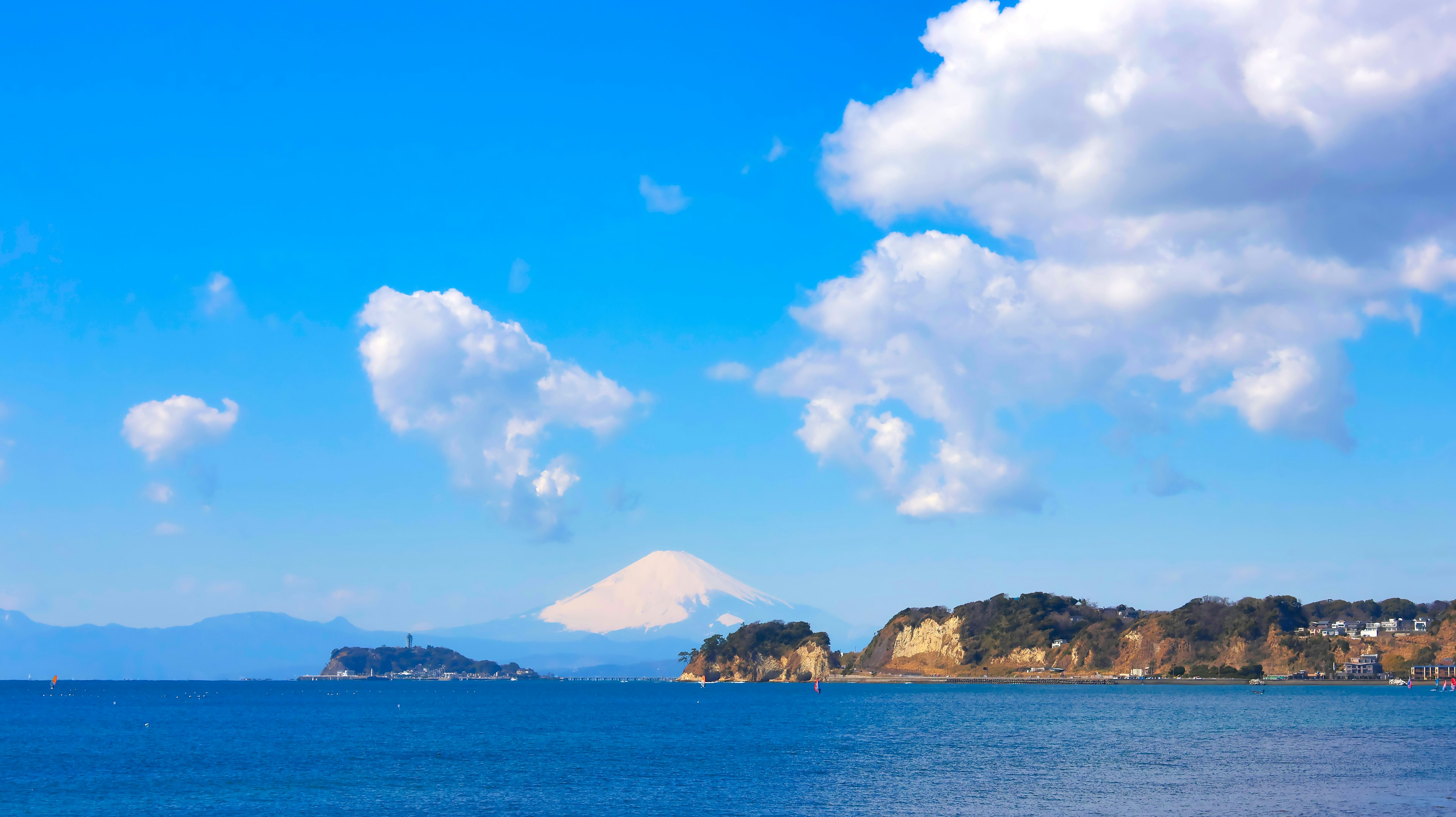 藍色海洋和天空的風景，白雲飄浮，富士山在遠處