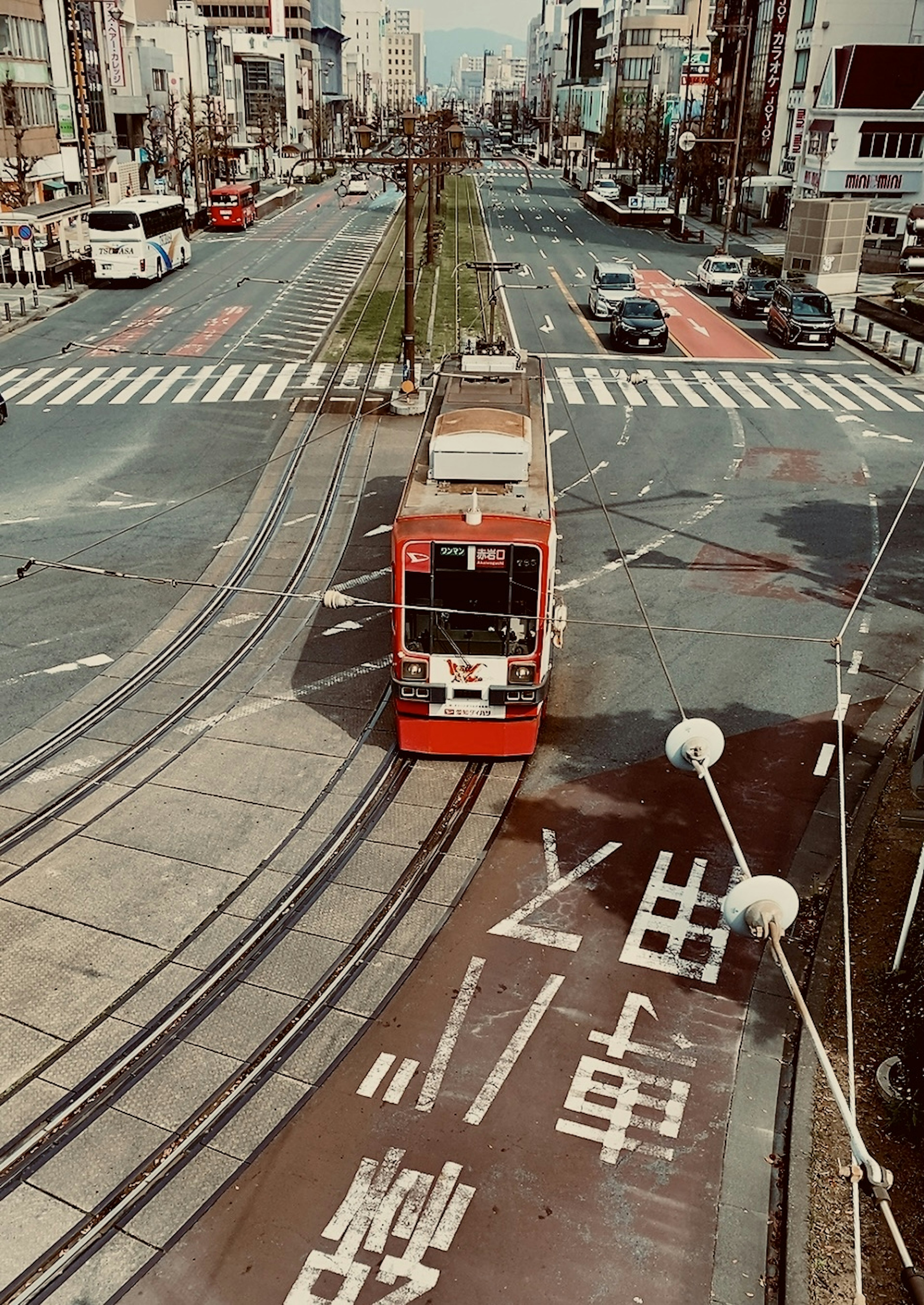 Rote Straßenbahn, die eine Kreuzung in einer Stadtlandschaft überquert