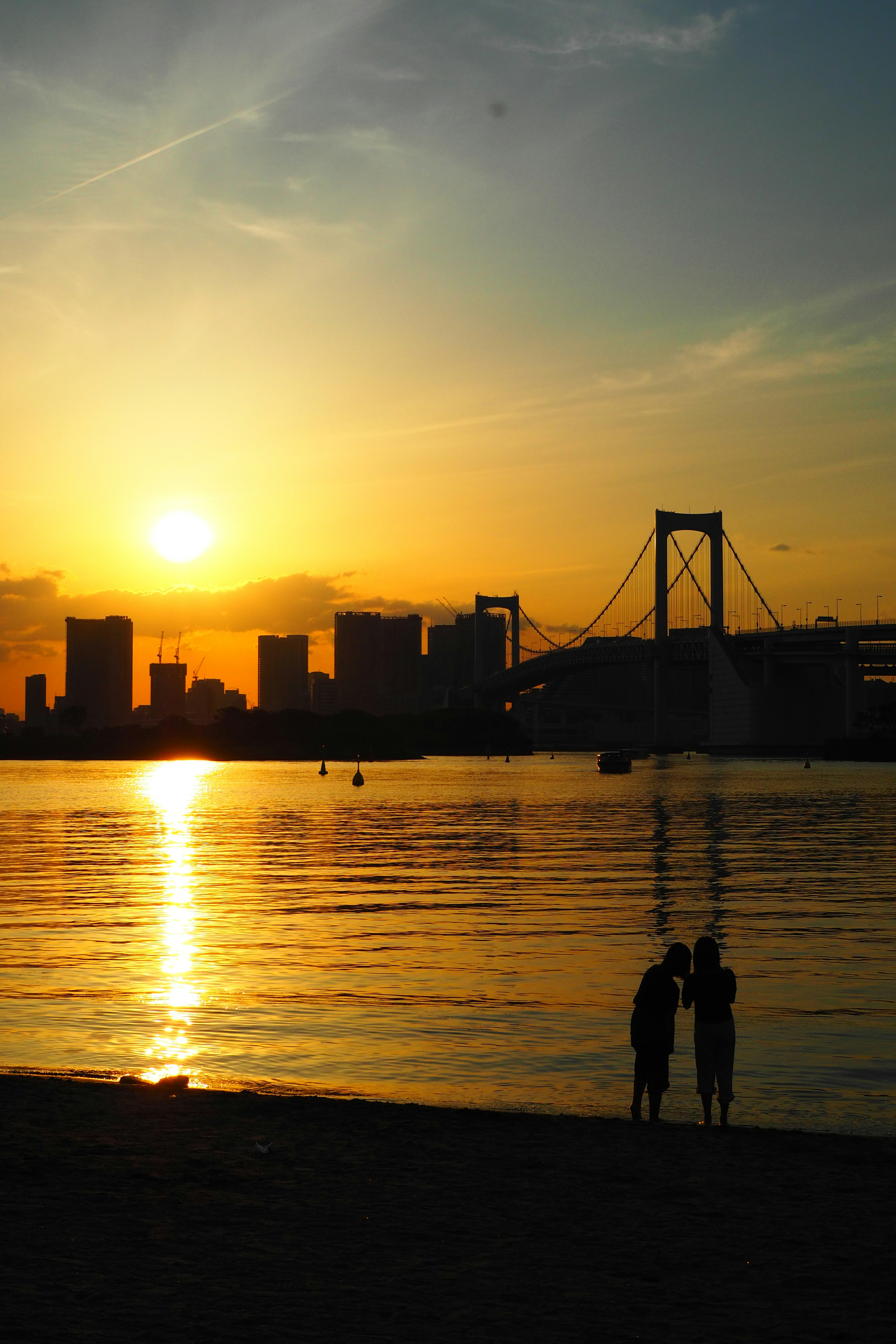 Couple en silhouette au coucher du soleil sur la baie de Tokyo et le pont Rainbow