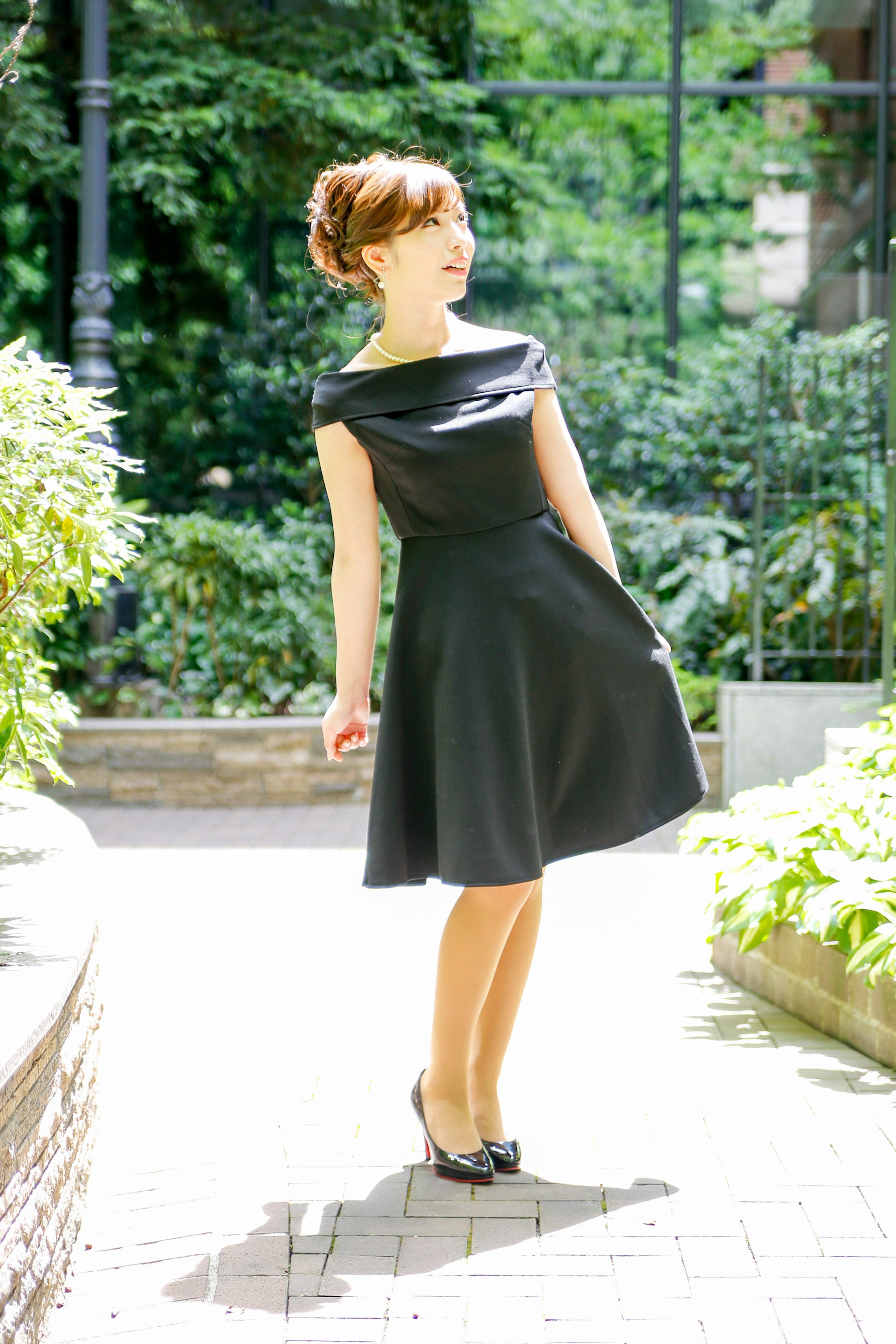 A woman in a black dress posing in a park