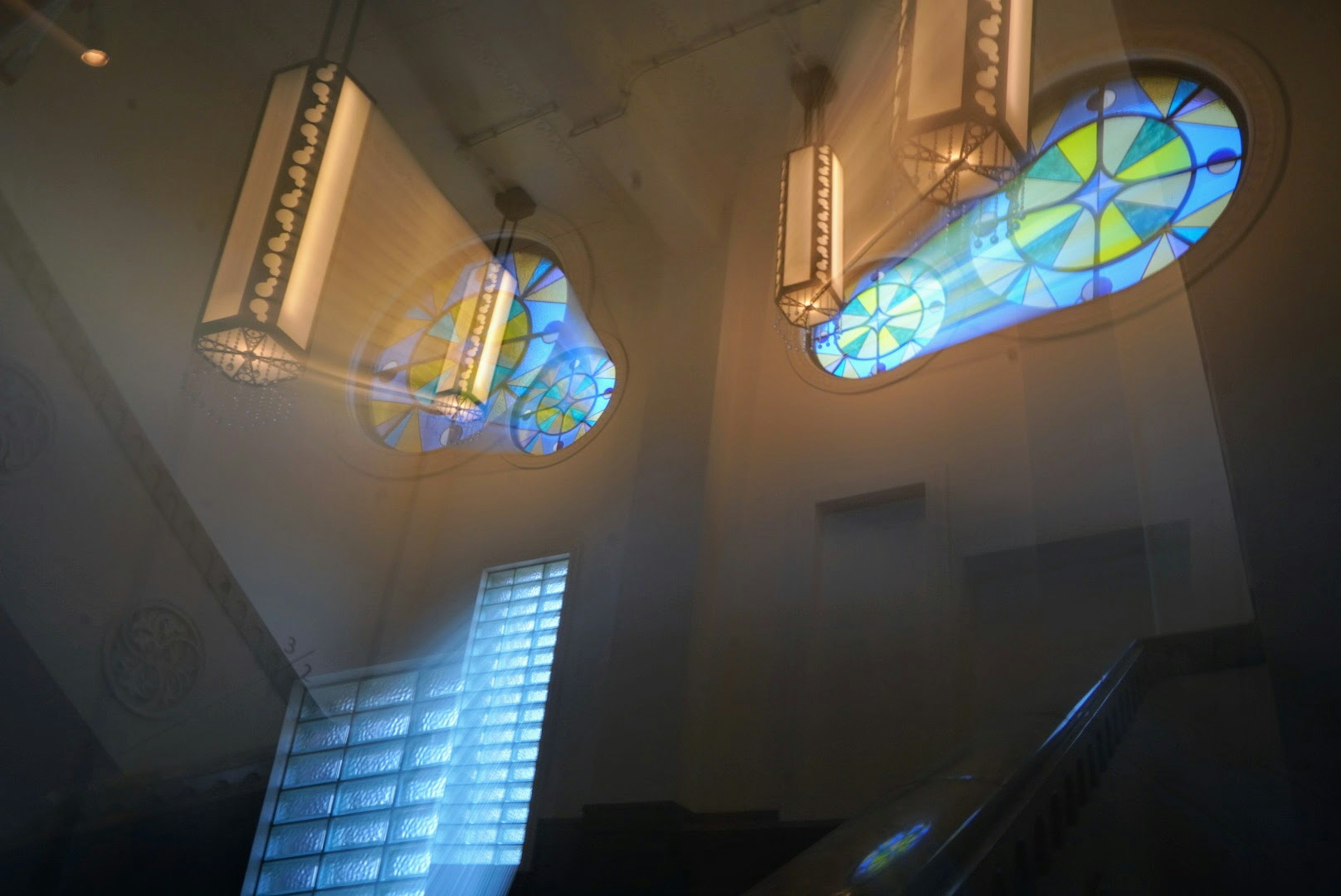 Interior view featuring blue and yellow stained glass windows and light fixtures