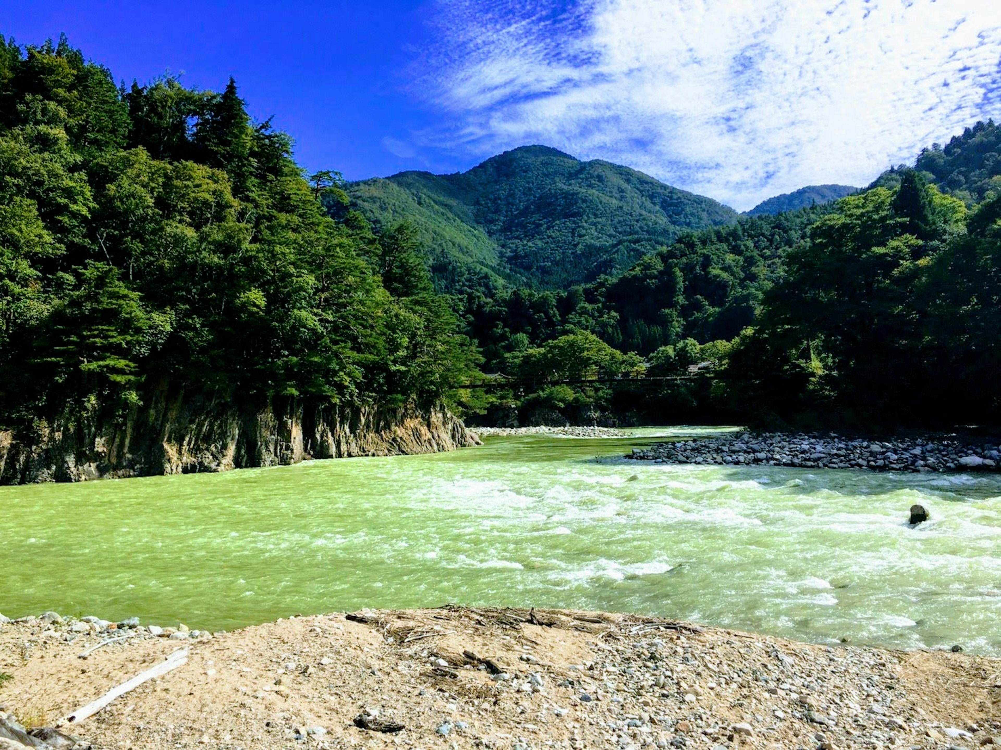 Paisaje natural con un río verde y montañas circundantes