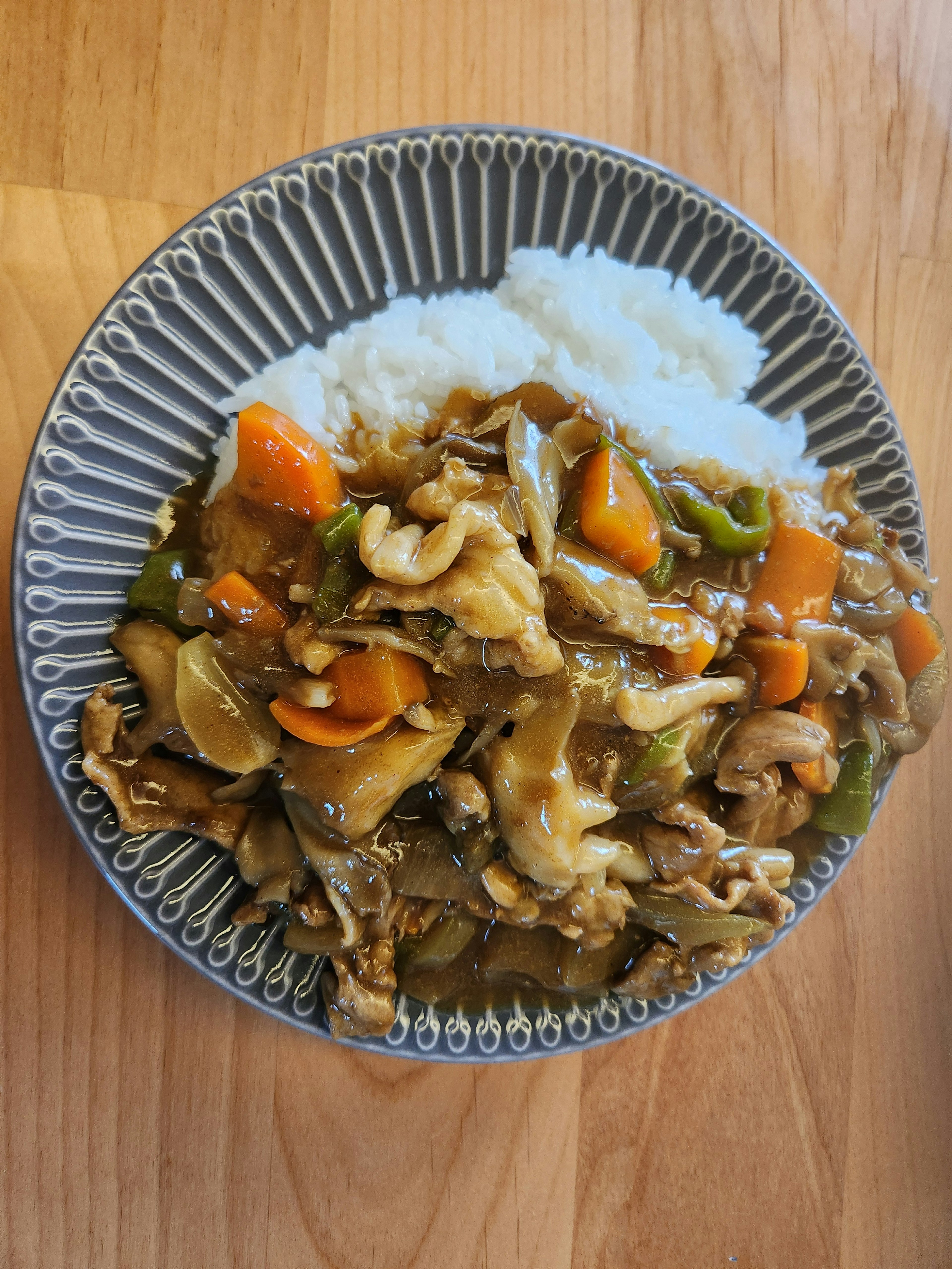 A plate of stir-fried vegetables and meat served with white rice