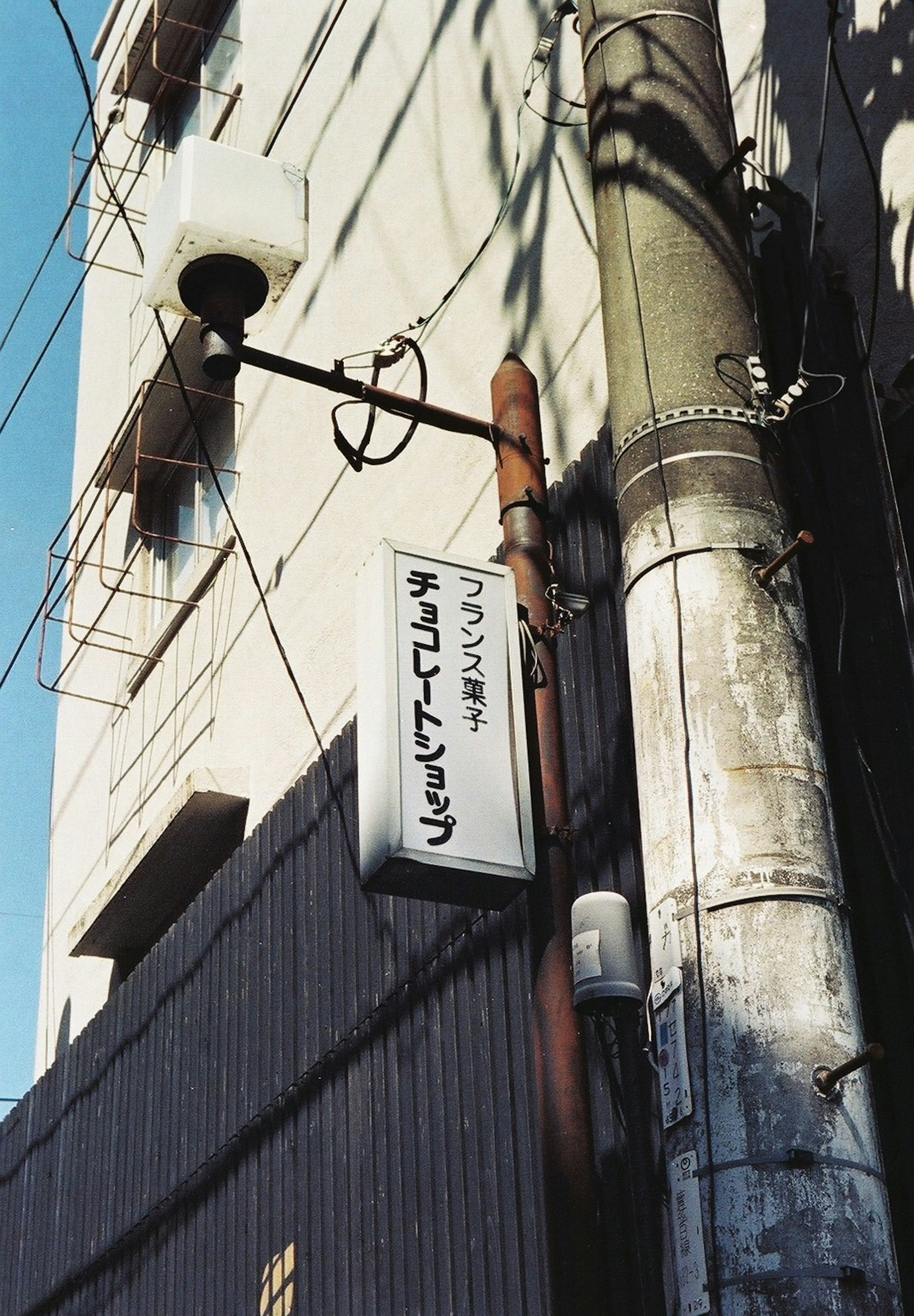 Imagen de un viejo letrero y un poste de servicios públicos en una esquina de la calle