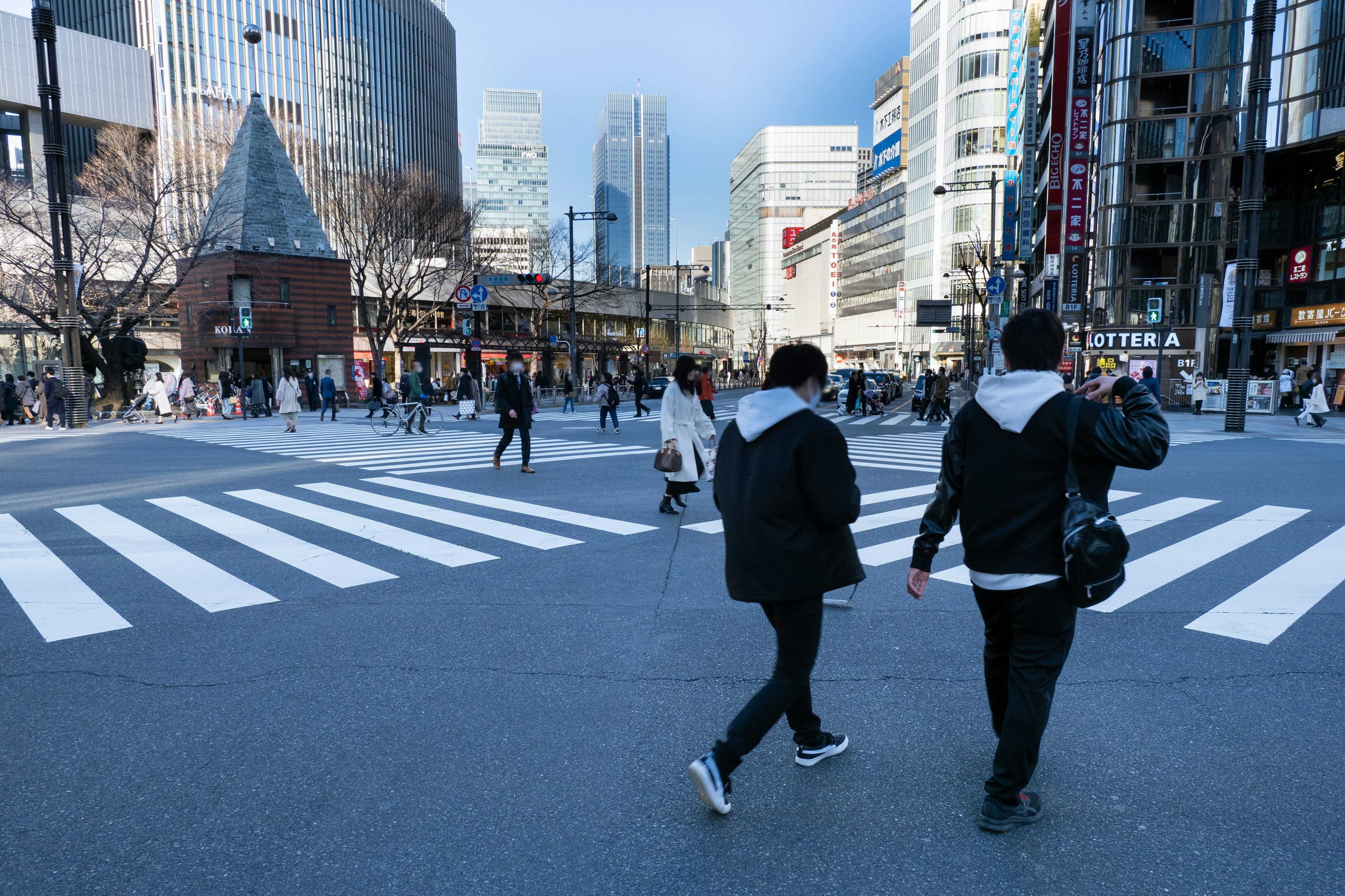 Escena de personas cruzando una intersección urbana con edificios modernos de fondo