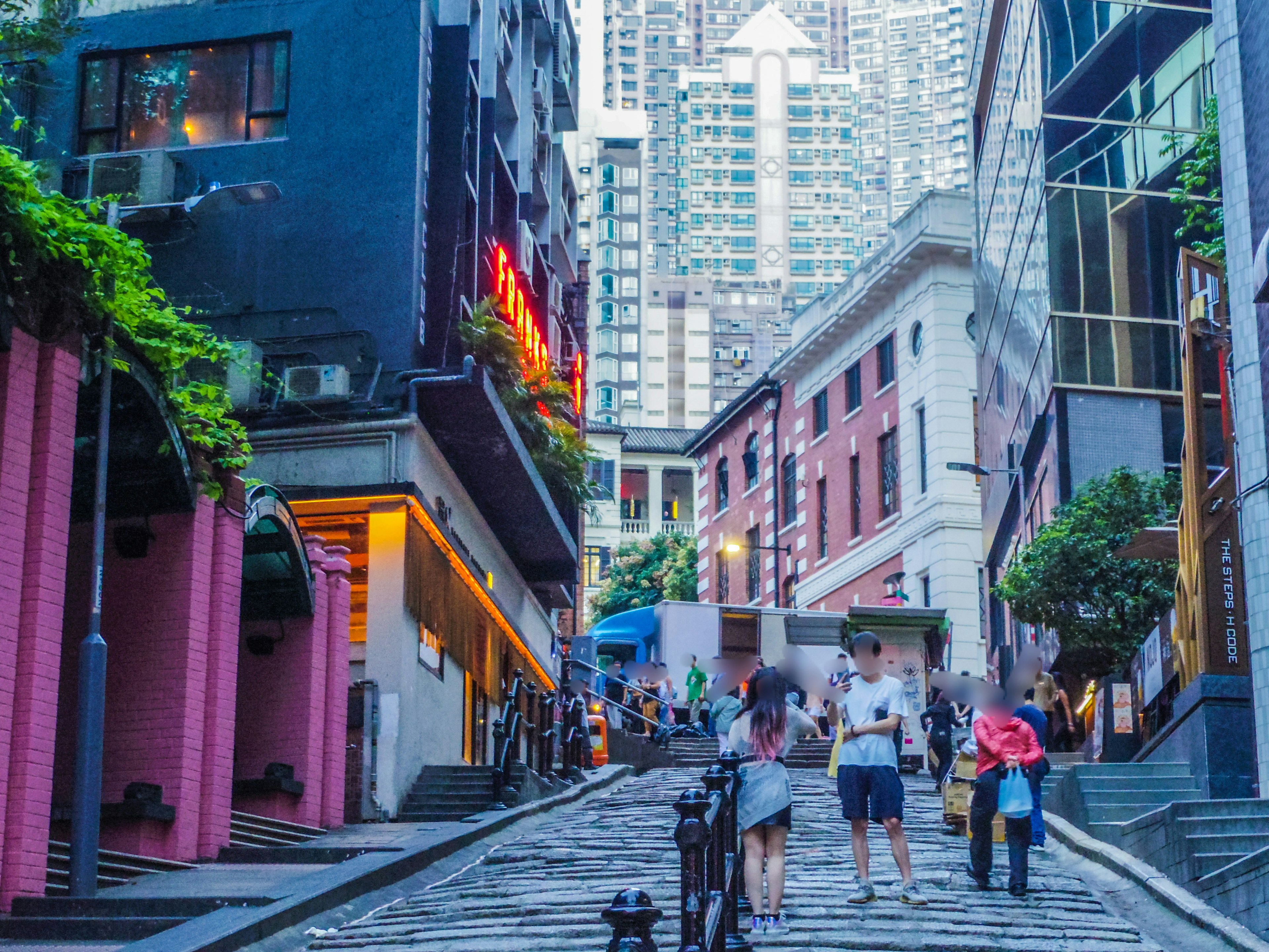 Busy urban street during twilight with people walking up the slope