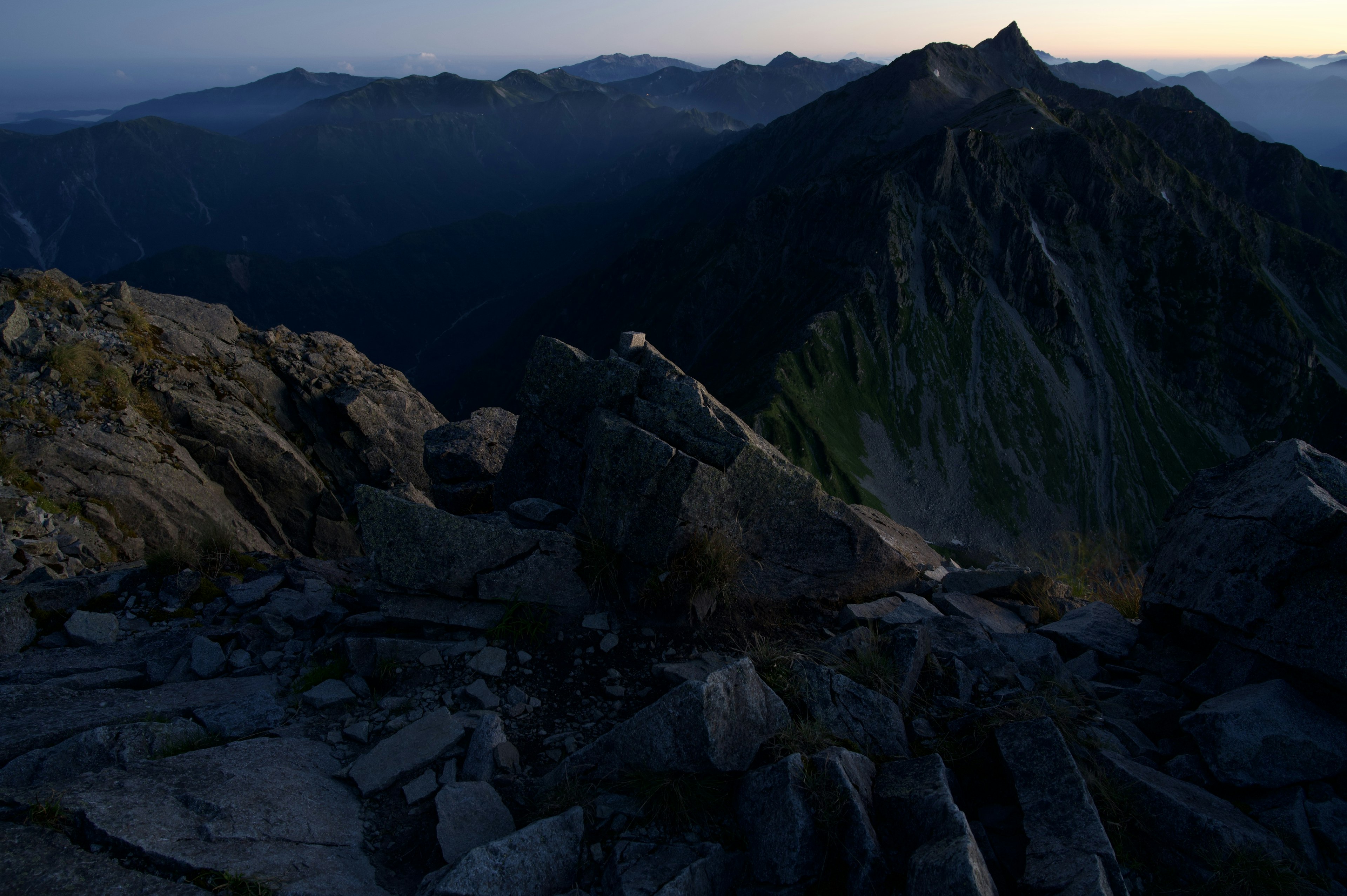 Berglandschaft bei Dämmerung mit felsigem Gelände und fernen Gipfeln