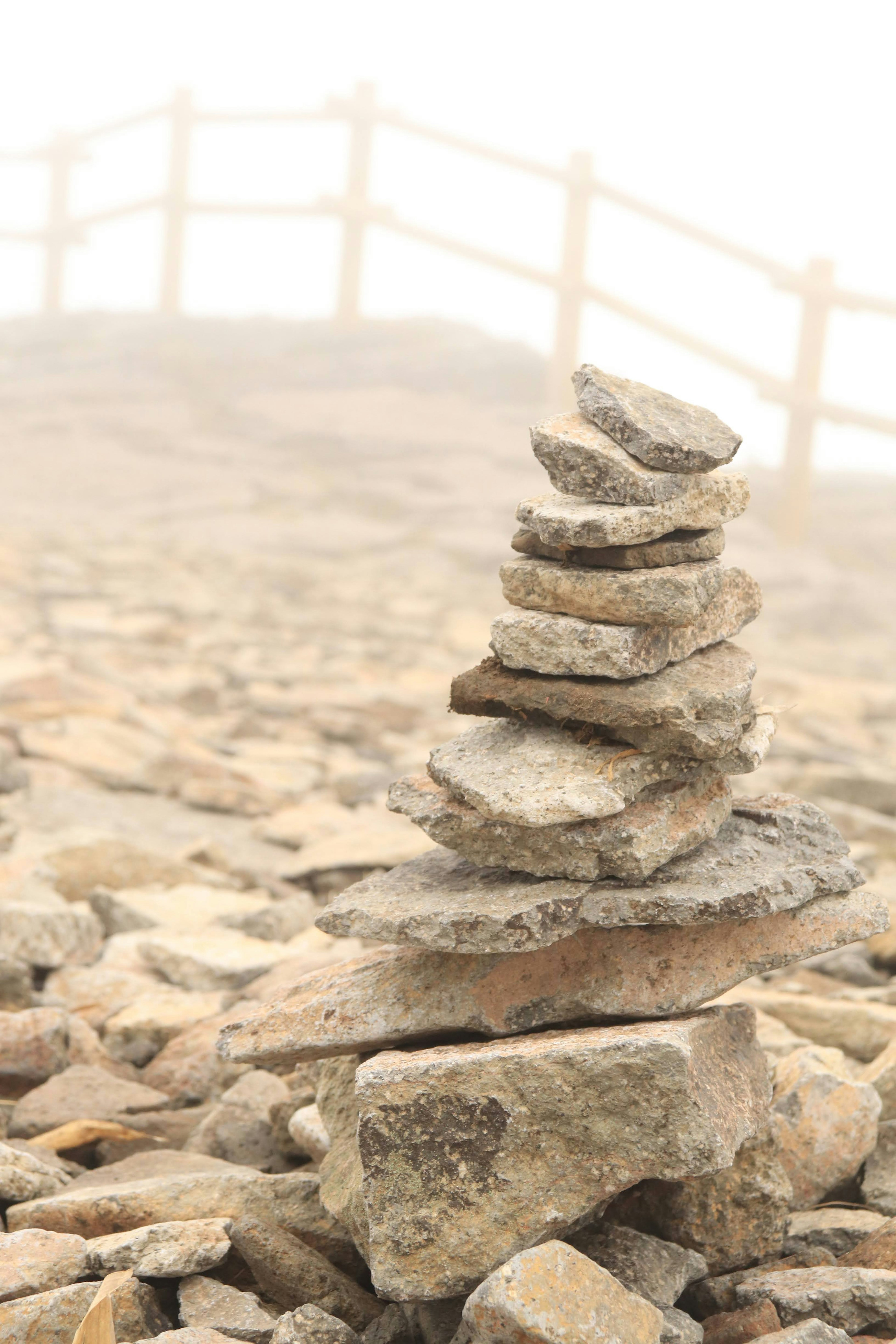 Pila de piedras en la niebla con una cerca de madera al fondo