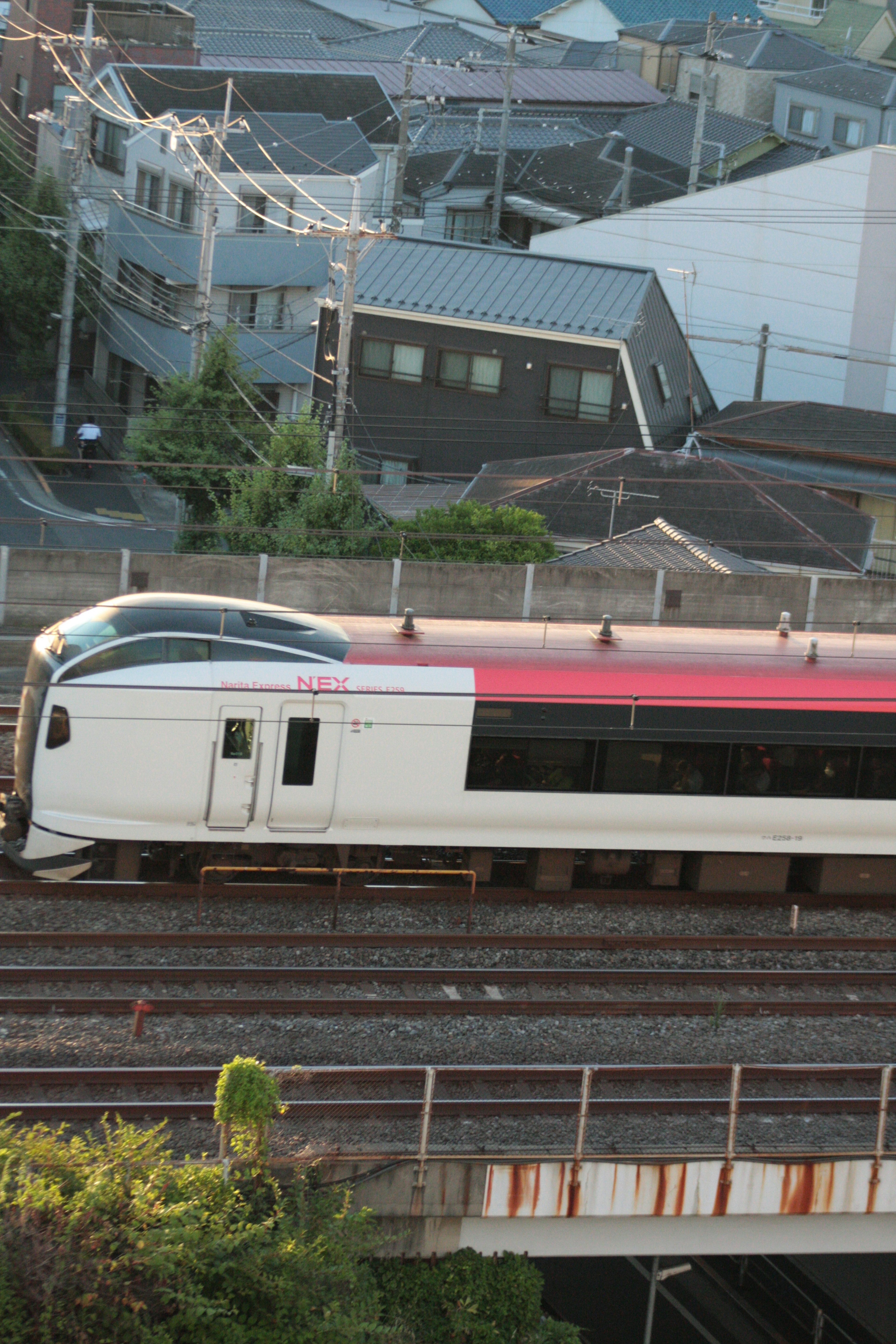 Shinkansen train passing on tracks with residential buildings in the background