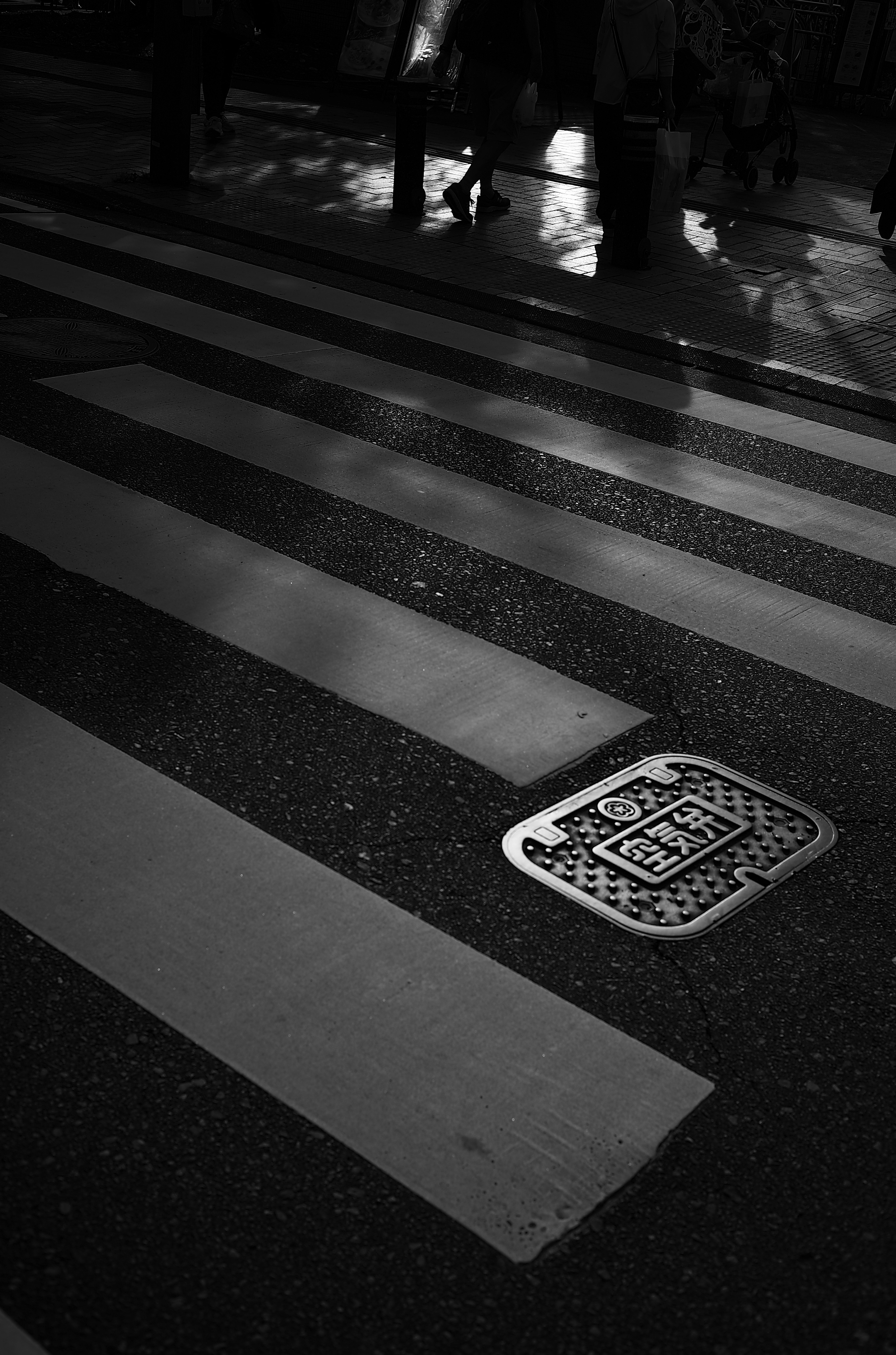 Paso de peatones en blanco y negro con una tapa de alcantarilla de código QR