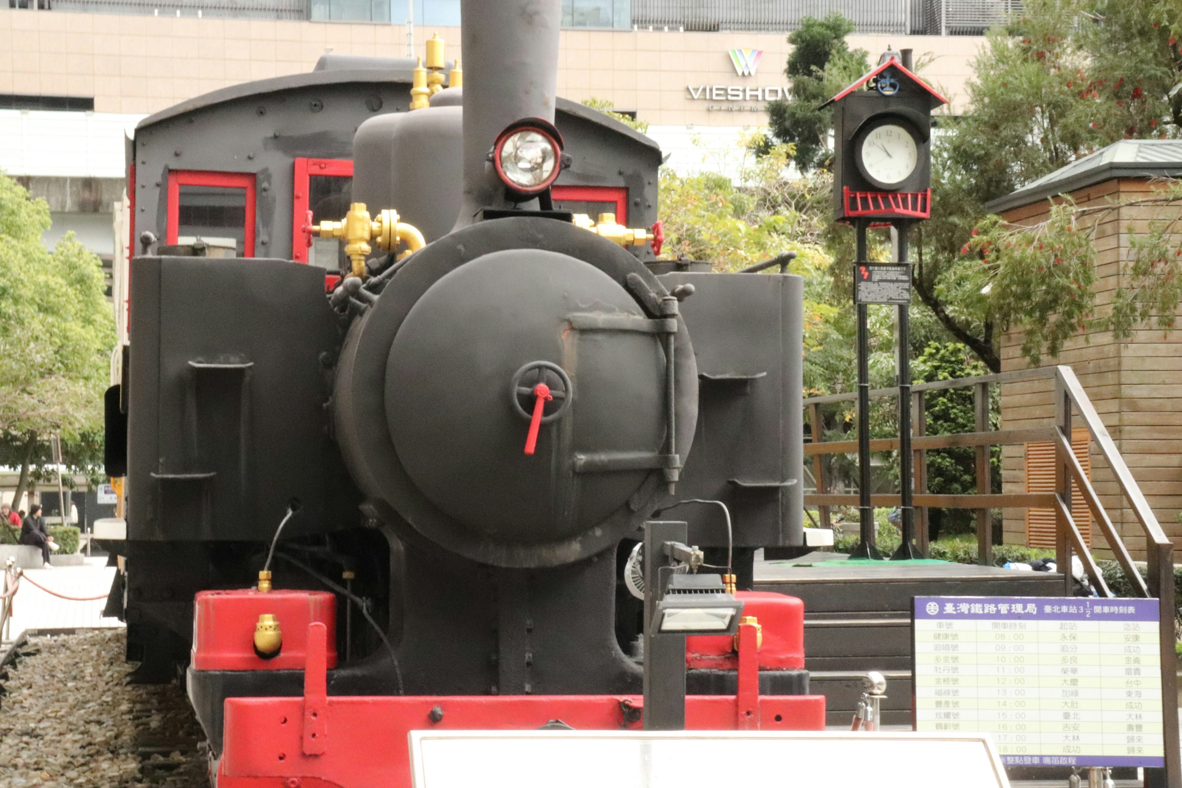 Locomotora de vapor negra con acentos rojos y un reloj