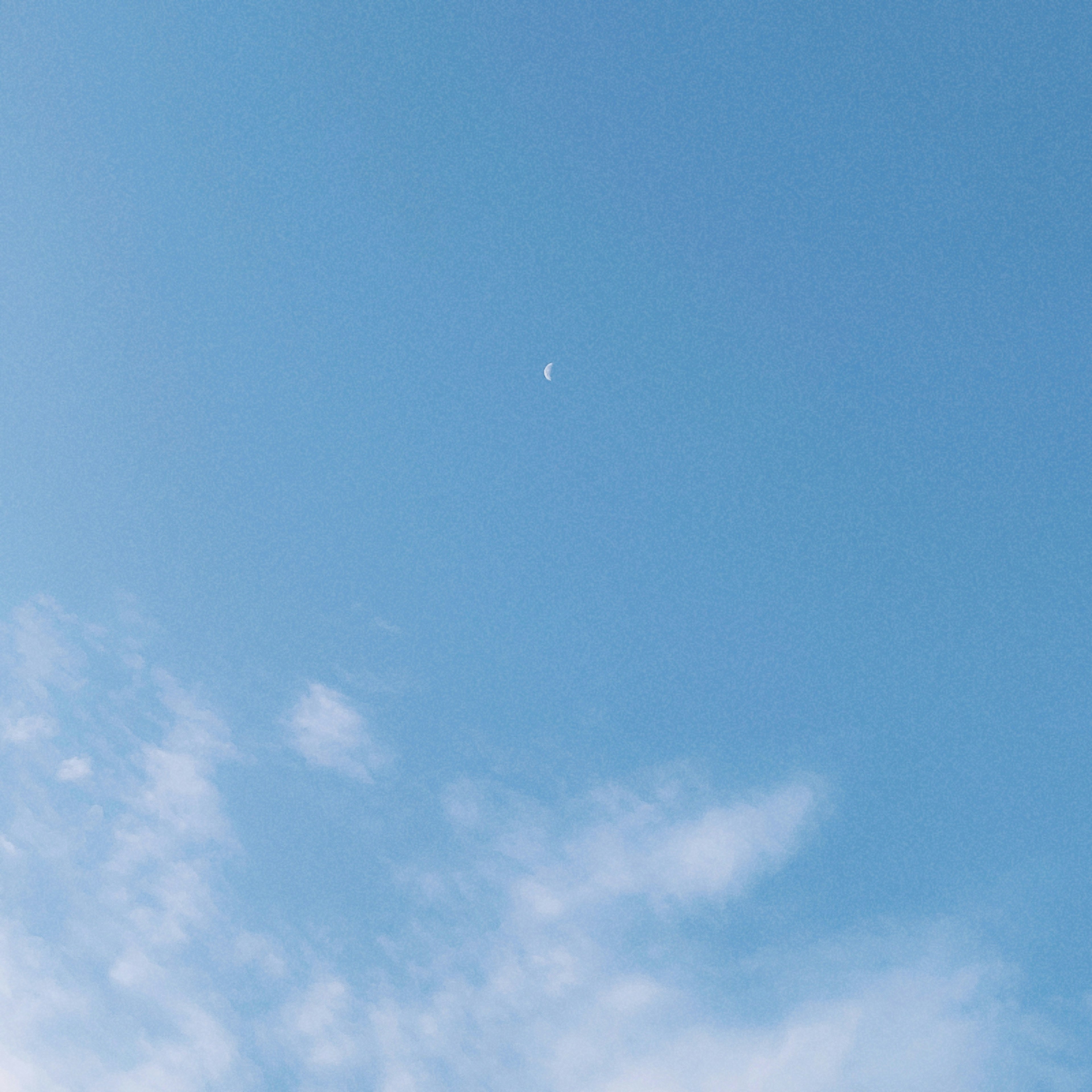 Ciel bleu clair avec une petite lune et des nuages doux