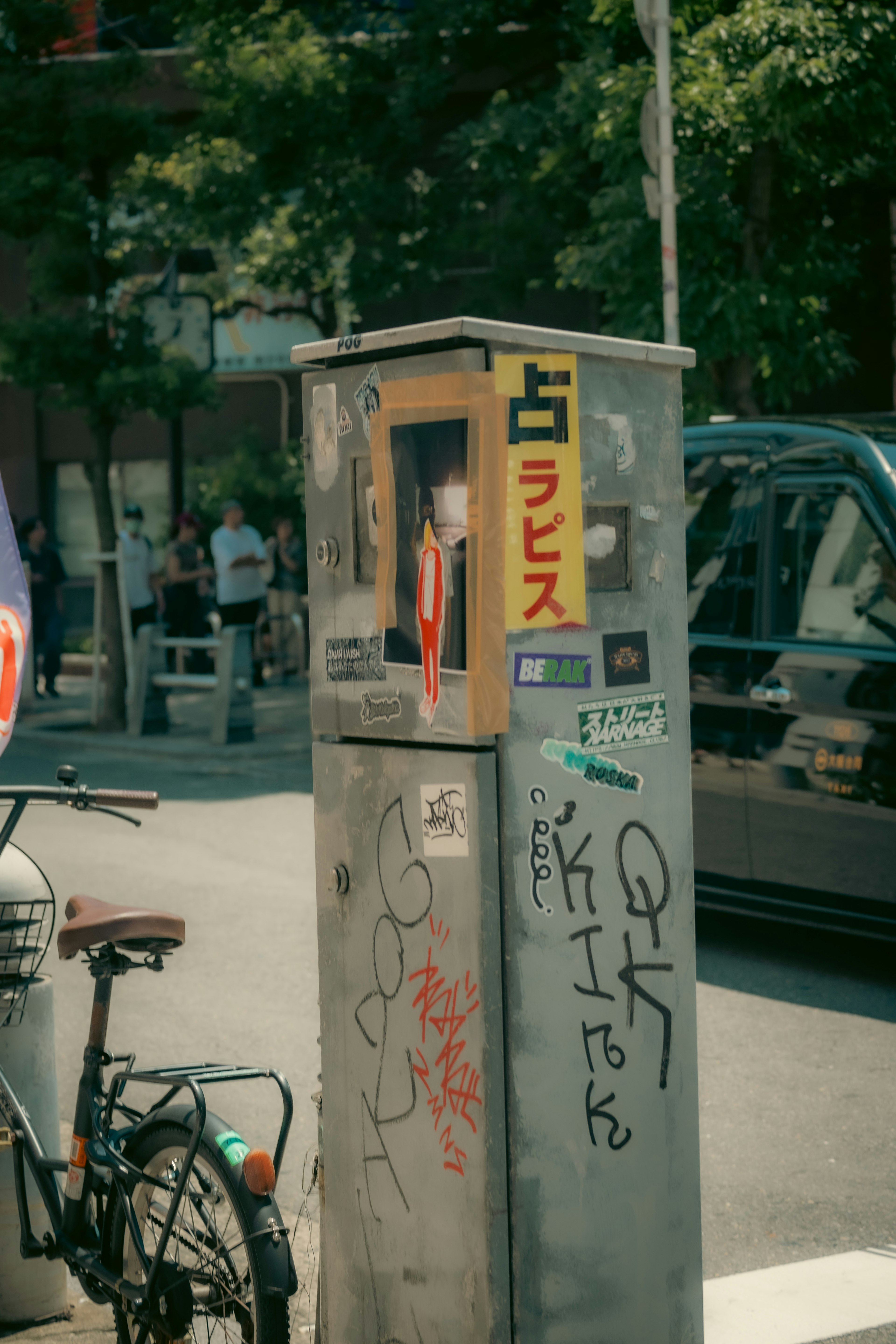 An old public telephone booth on the street corner with a bicycle nearby