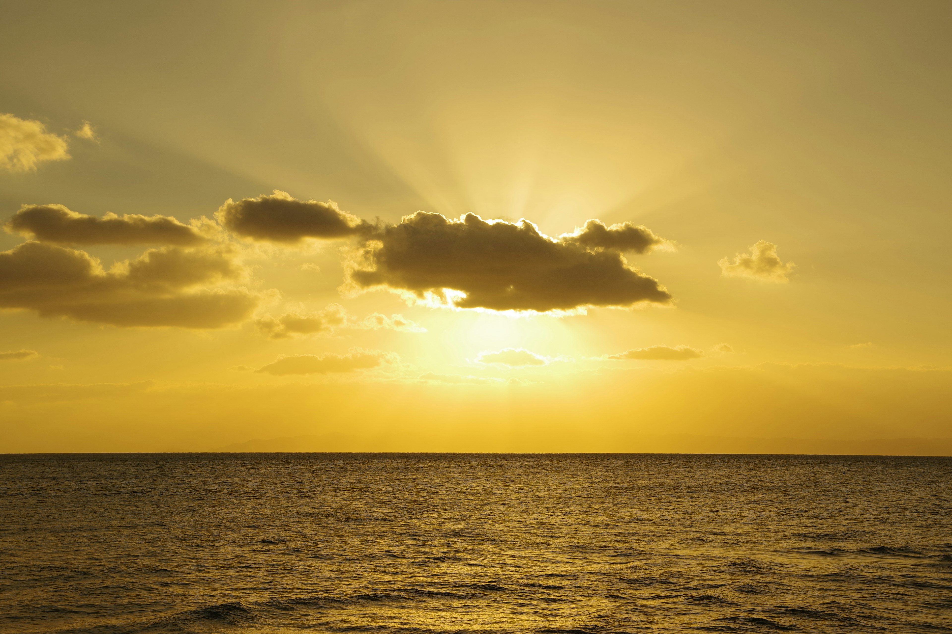 Atardecer dorado sobre el océano con nubes