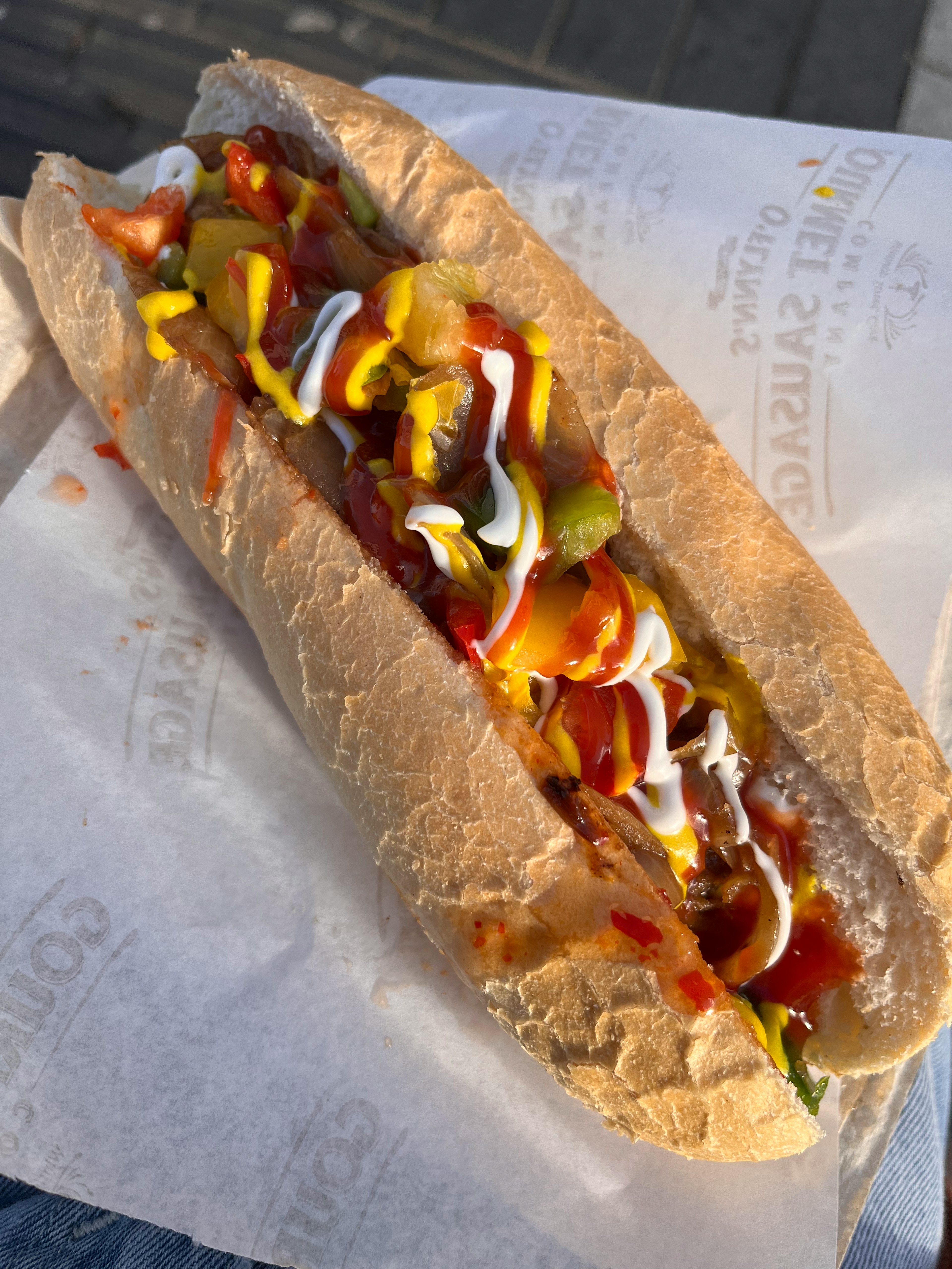 Un hot dog con ketchup, senape, maionese, cetriolini e formaggio