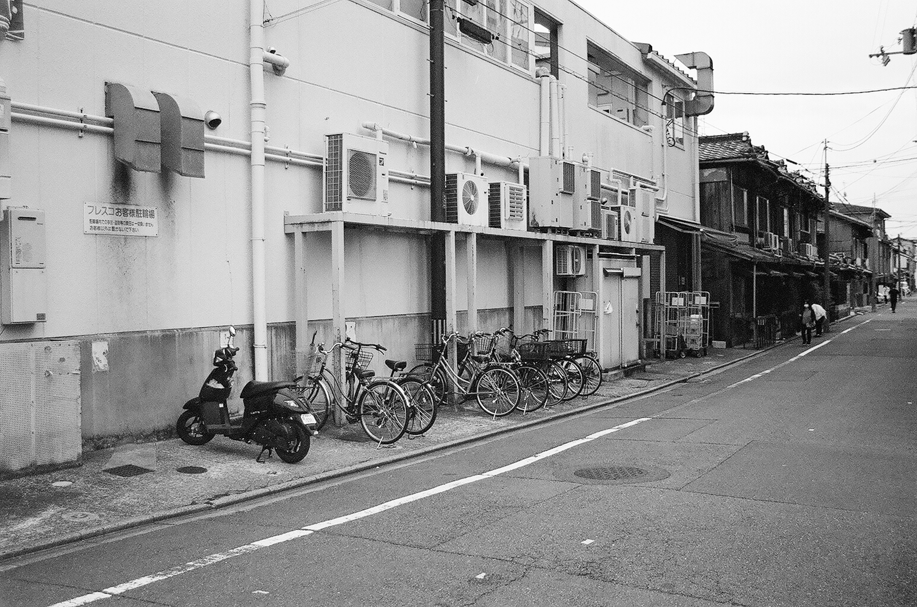 Scène de rue en noir et blanc avec des vélos et un scooter