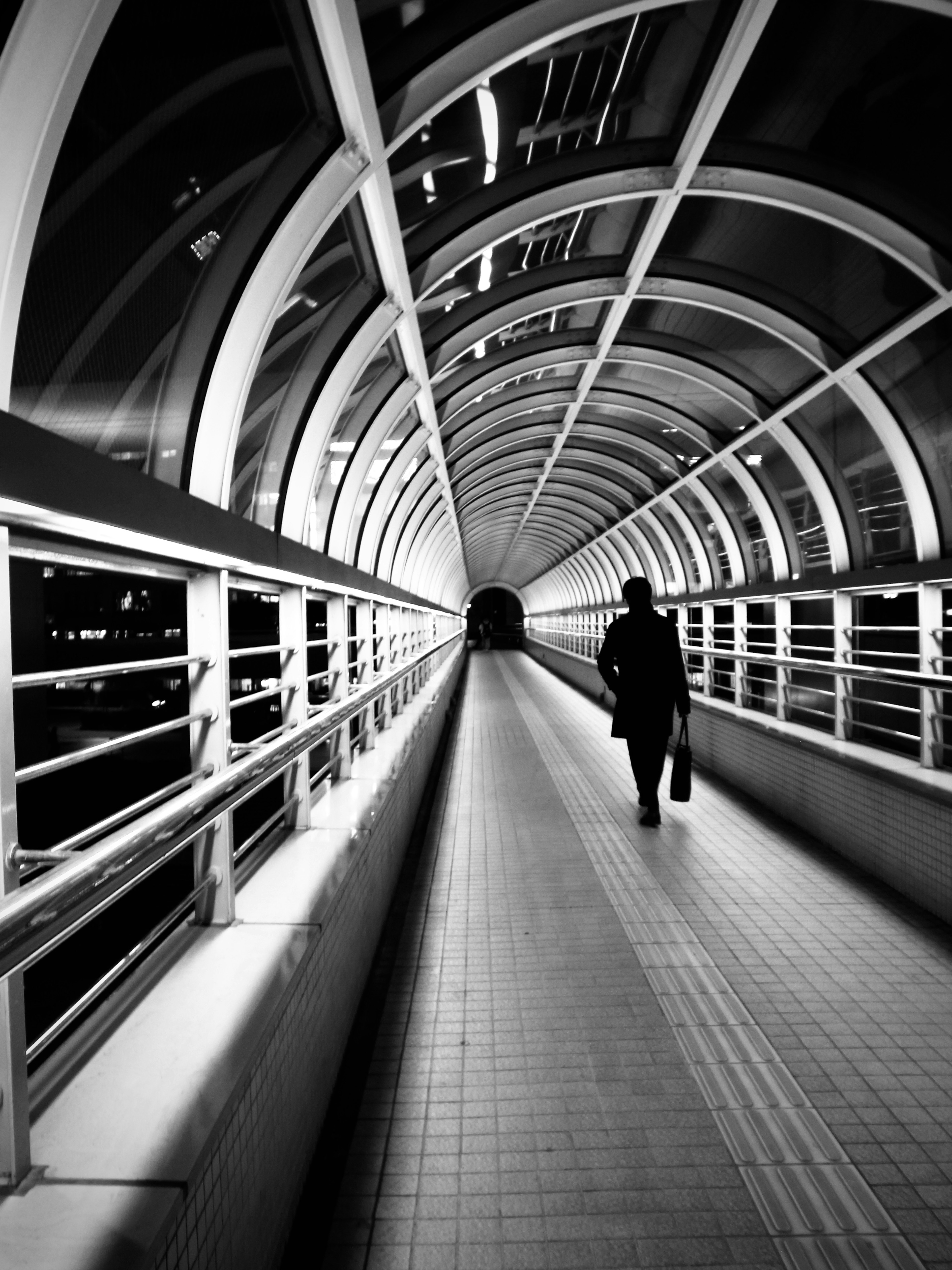 Silhouette einer Person, die in einem Tunnel in Schwarzweiß geht