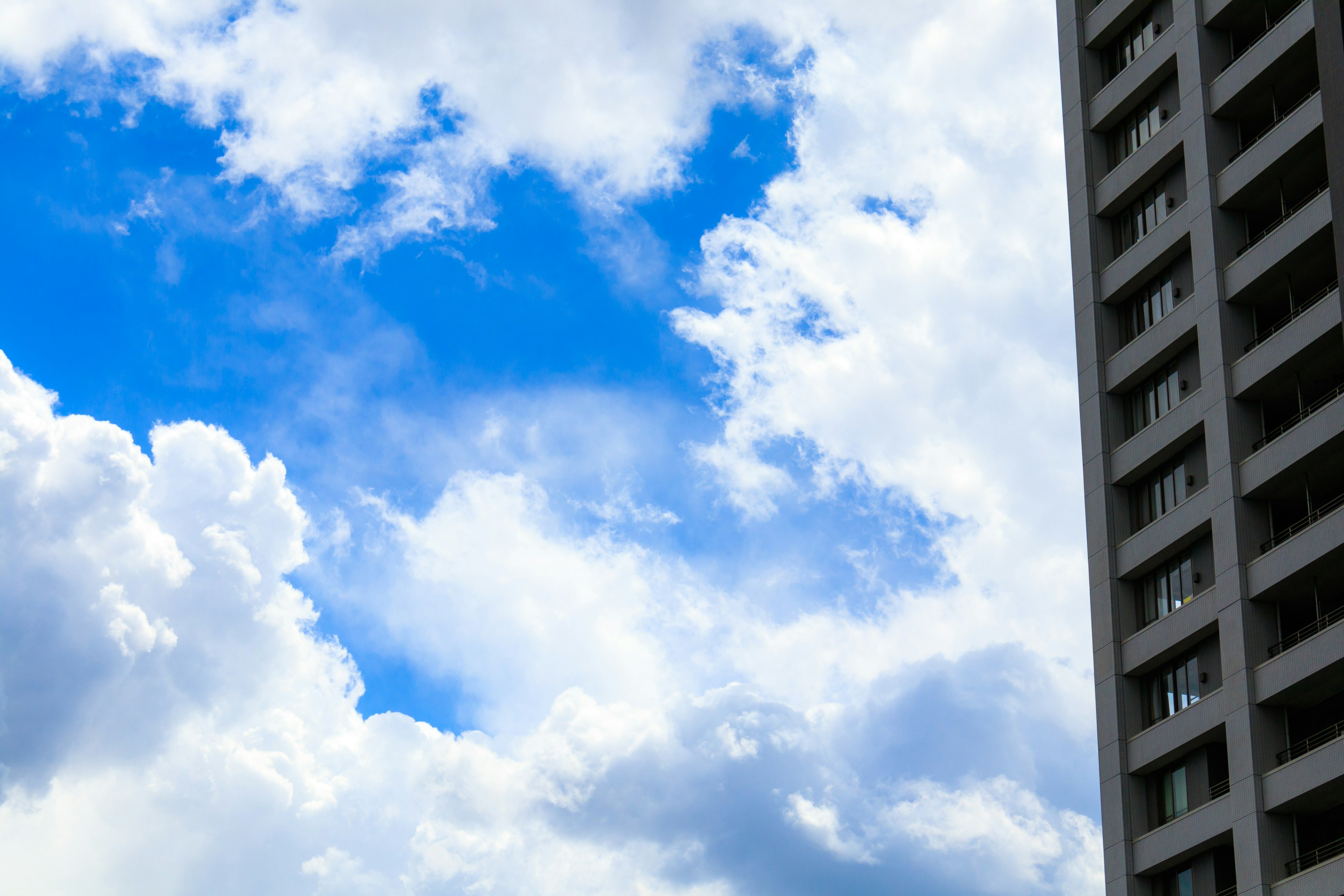 Ein Hochhaus vor einem Hintergrund aus blauem Himmel und weißen Wolken