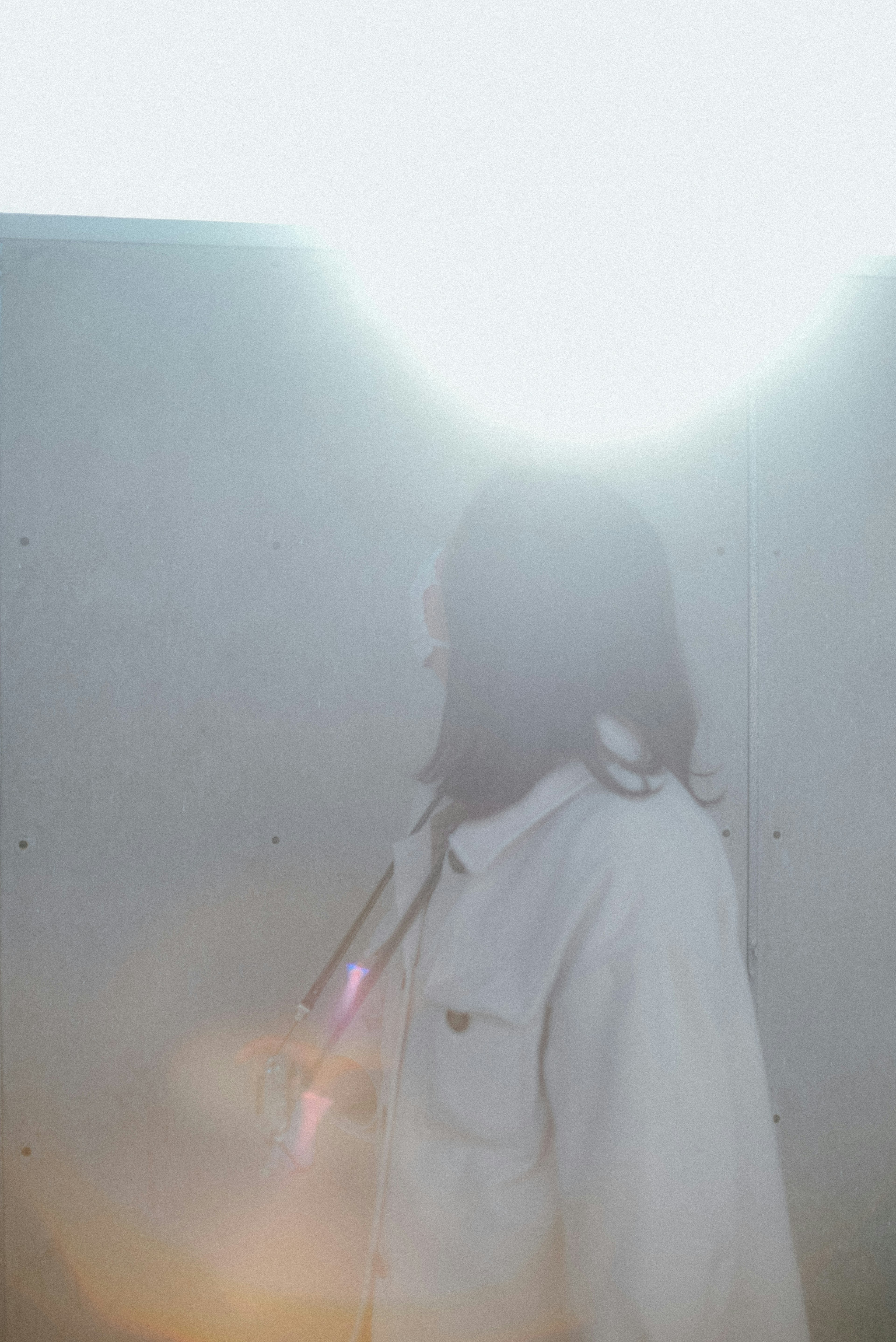 Silhouette of a woman standing in front of a wall illuminated by bright light