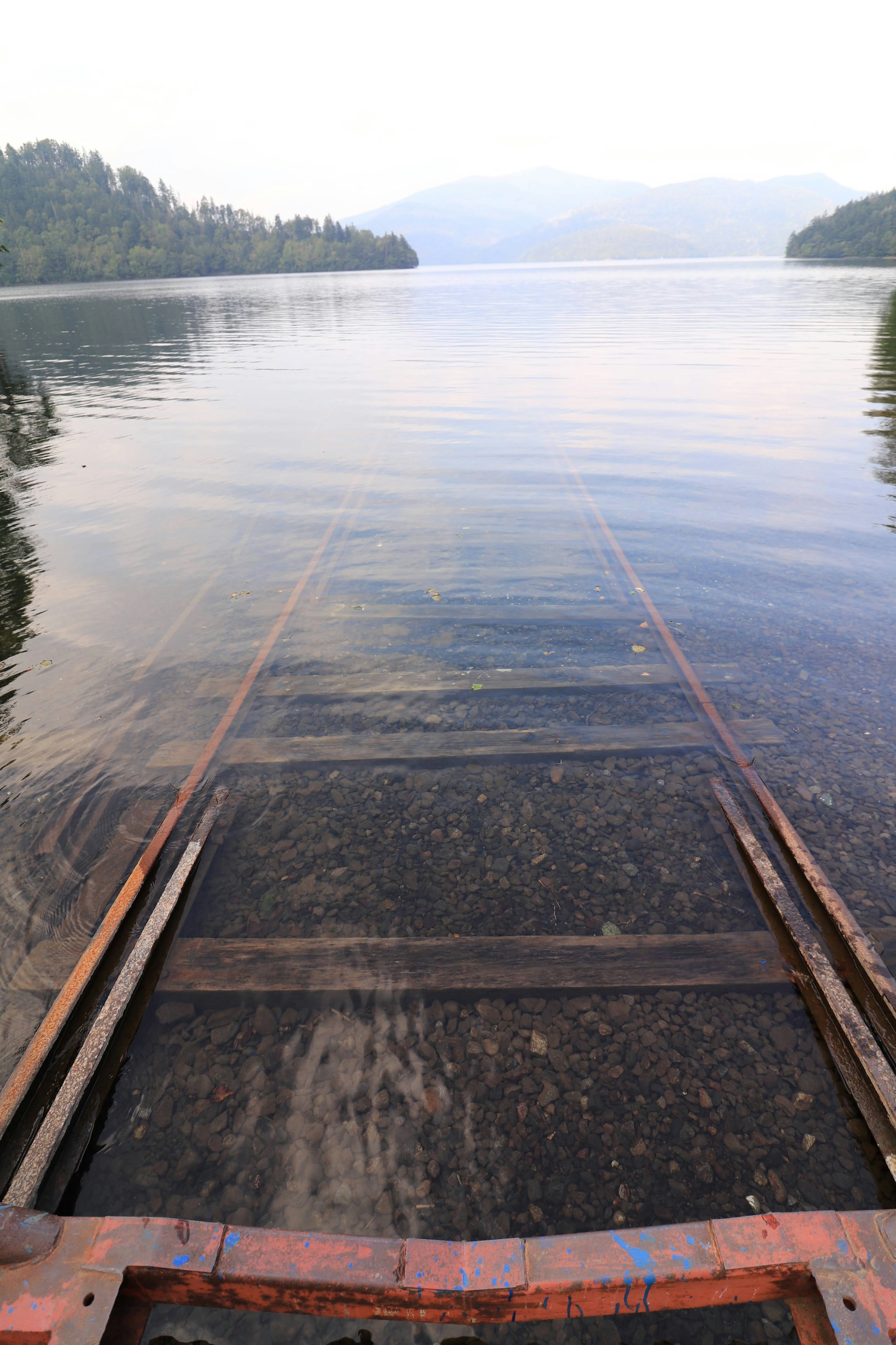 Rampe en métal menant à un lac calme avec des montagnes environnantes