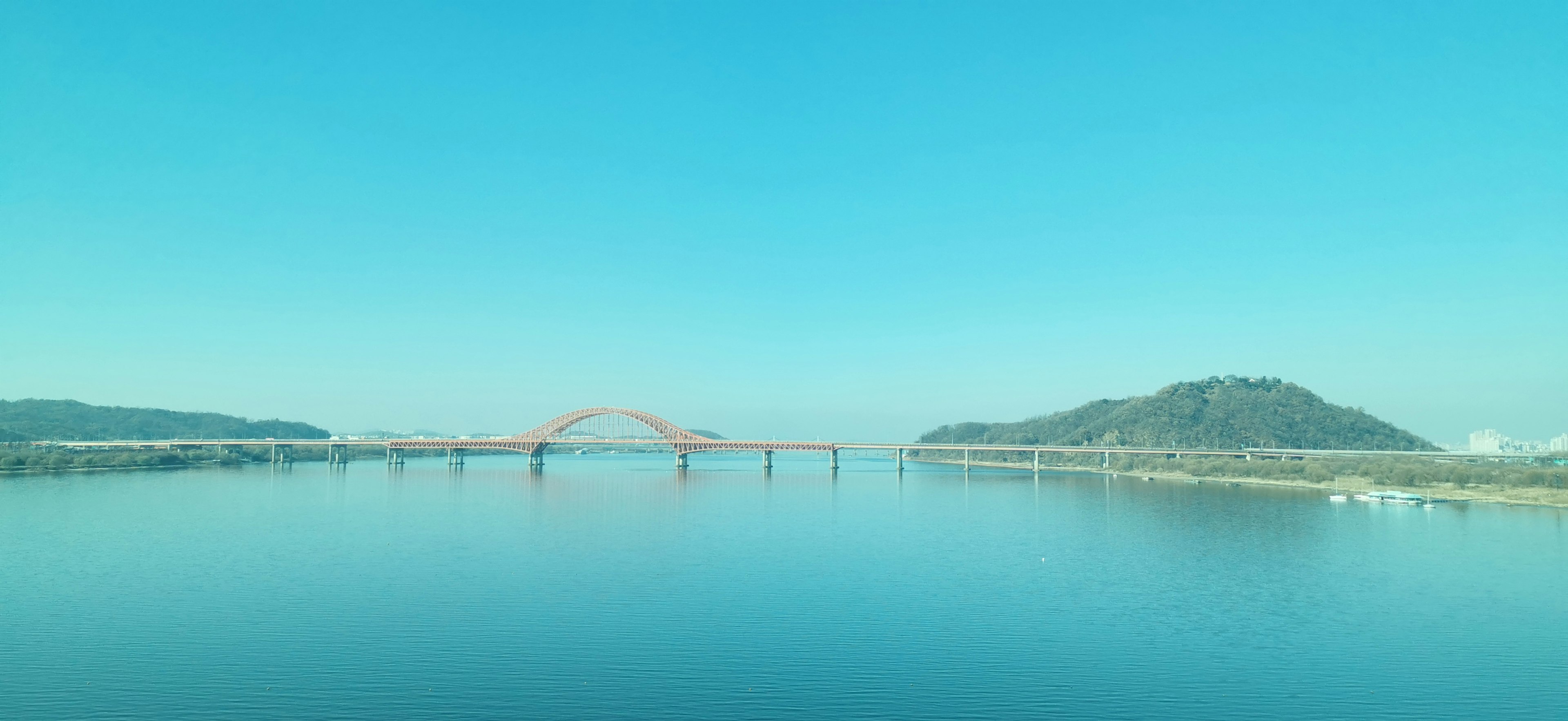 青空と静かな水面に赤い橋が映る風景