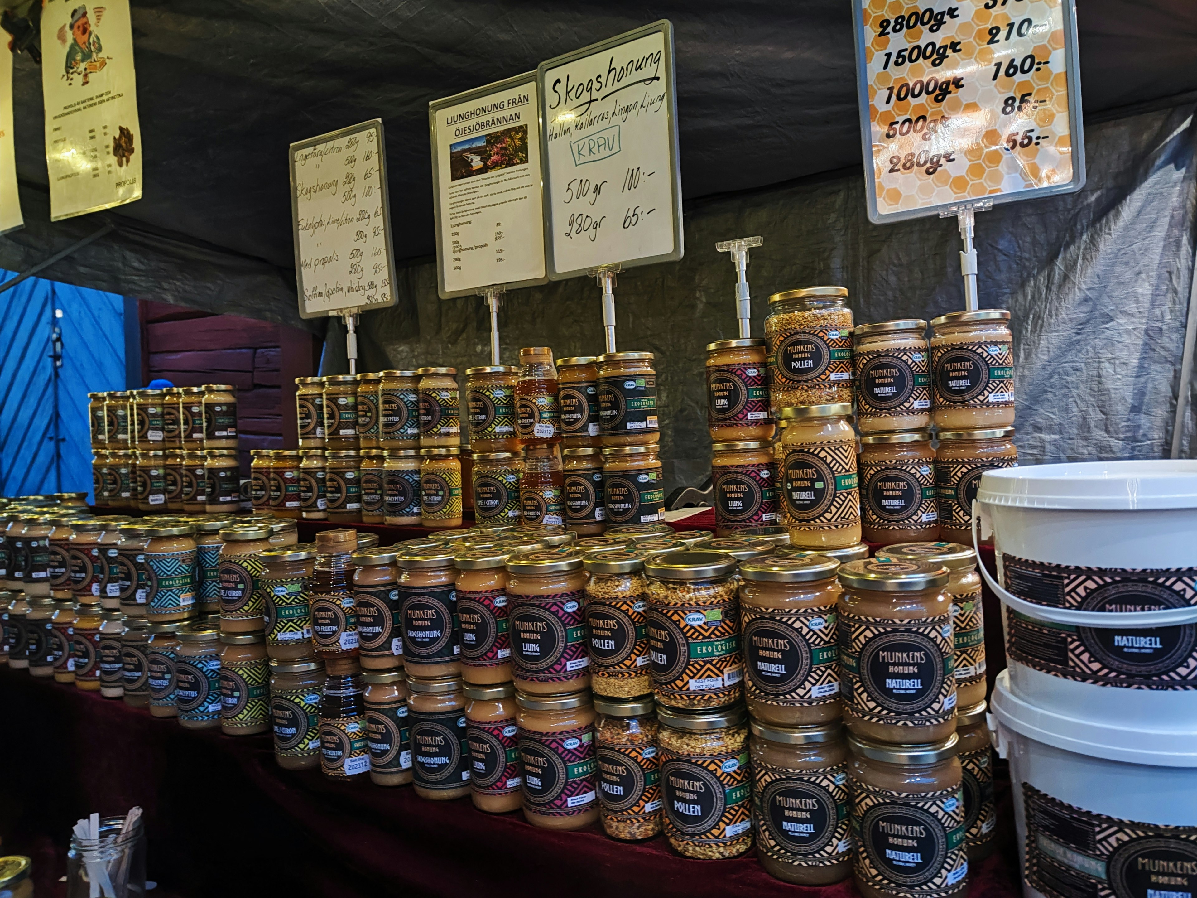 Interno di una bancarella di mercato con barattoli di marmellate e sottaceti