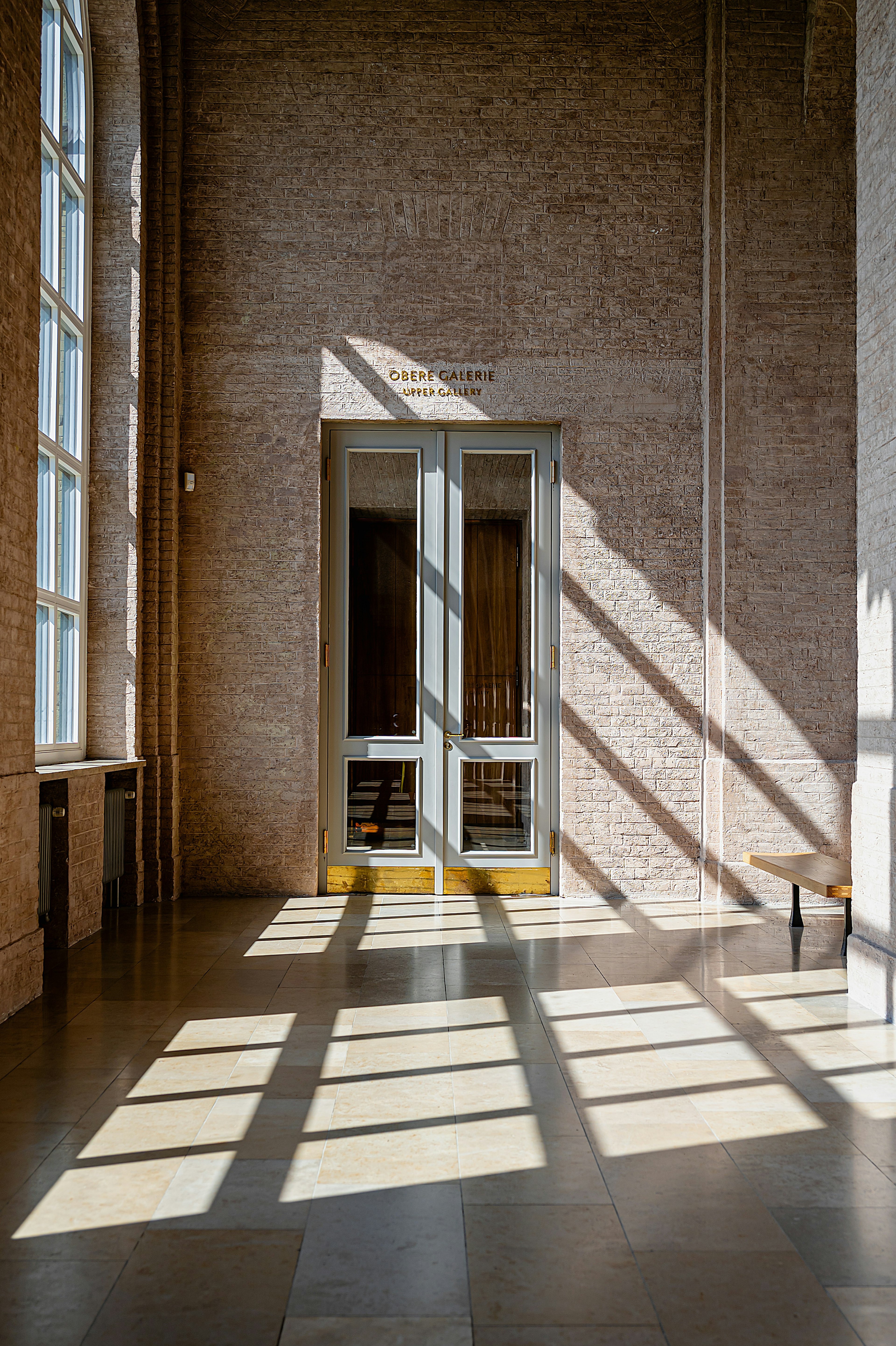 Innenansicht eines Raumes mit Sonnenlicht, das Schatten durch große Fenster wirft