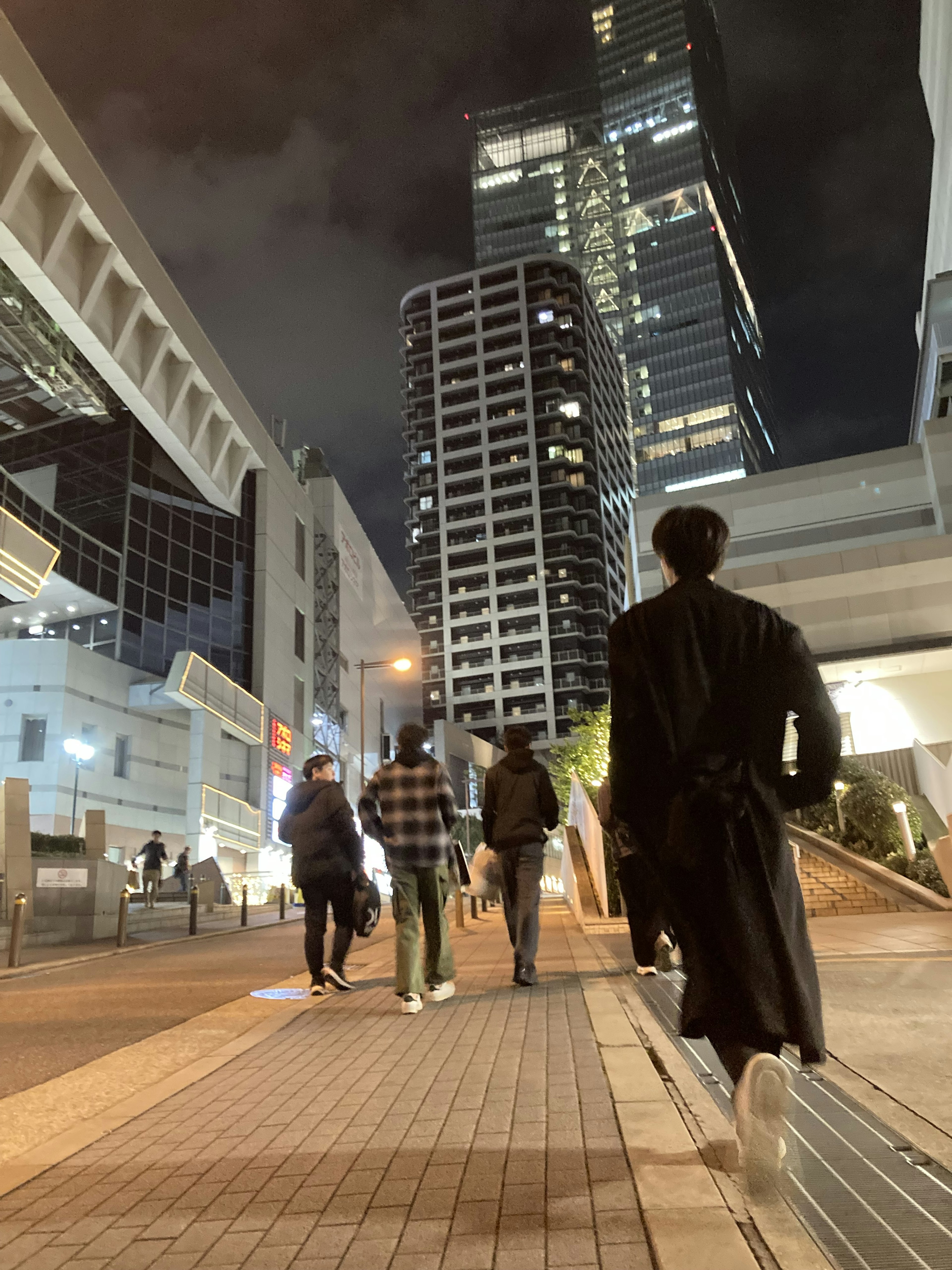 夜の都市を歩く人々のグループ 高層ビルが背景にある