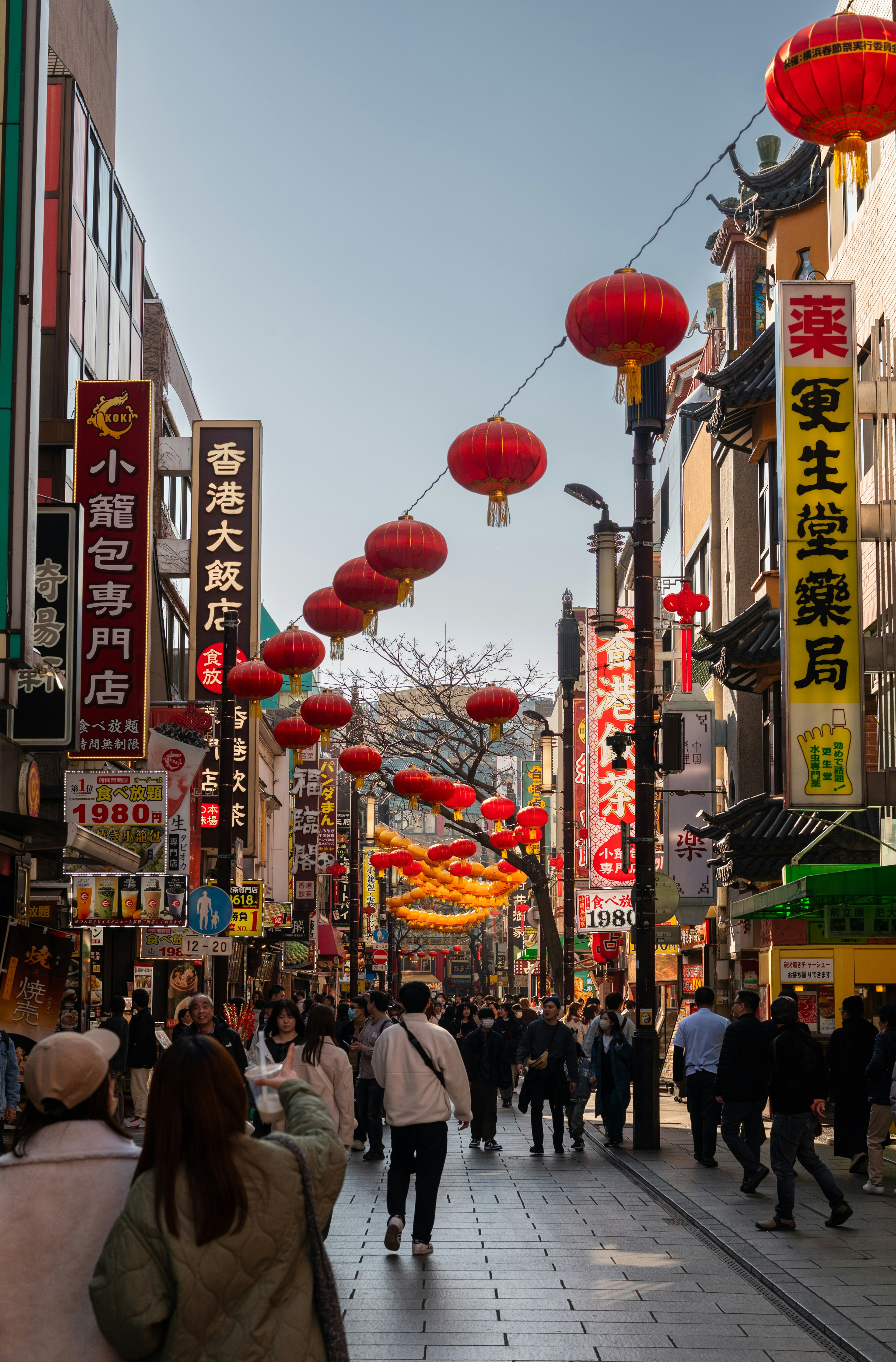 Une scène de rue vibrante dans le quartier chinois avec des lanternes colorées suspendues au-dessus