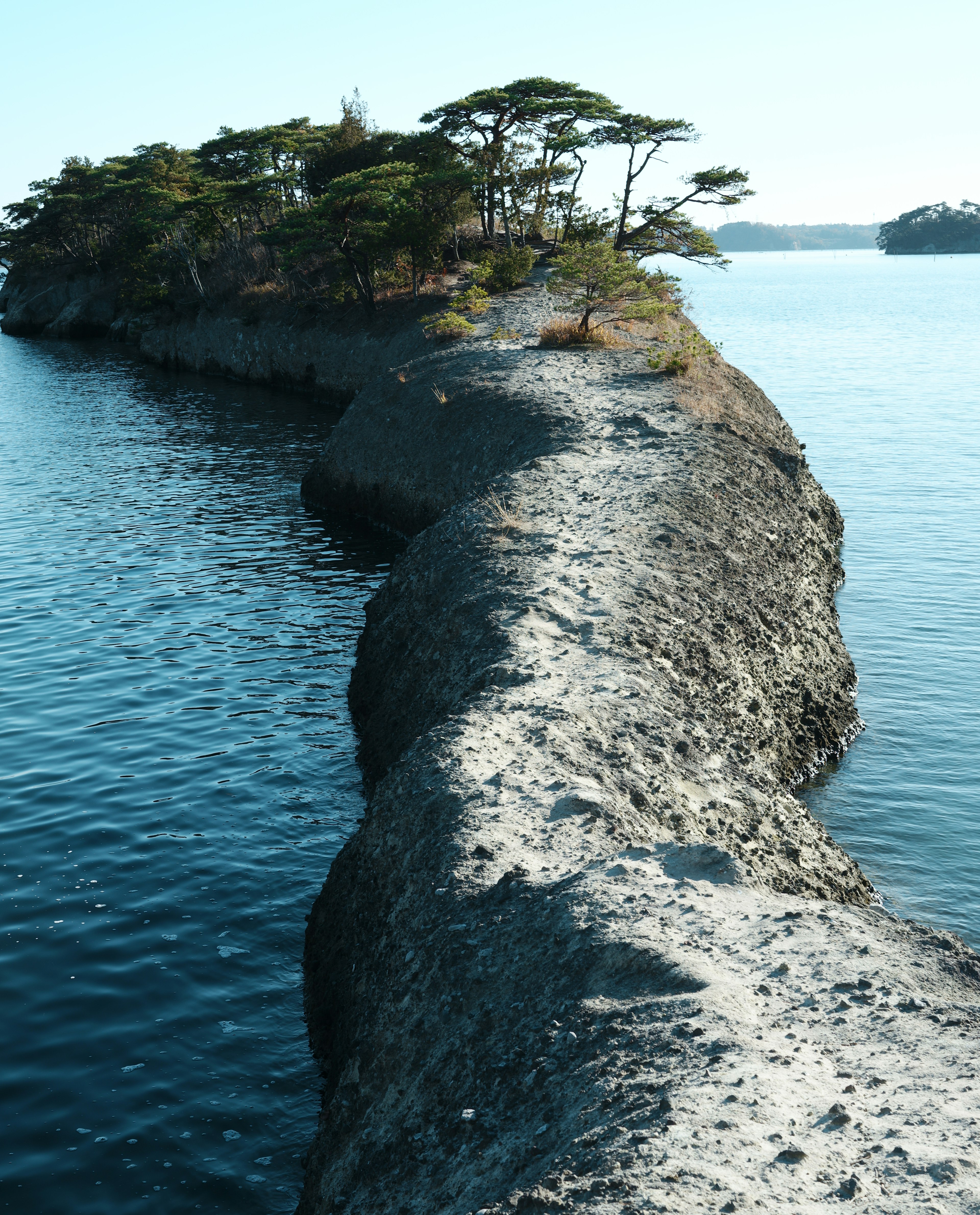 Sendero arenoso estrecho que lleva a una pequeña isla rodeada de agua