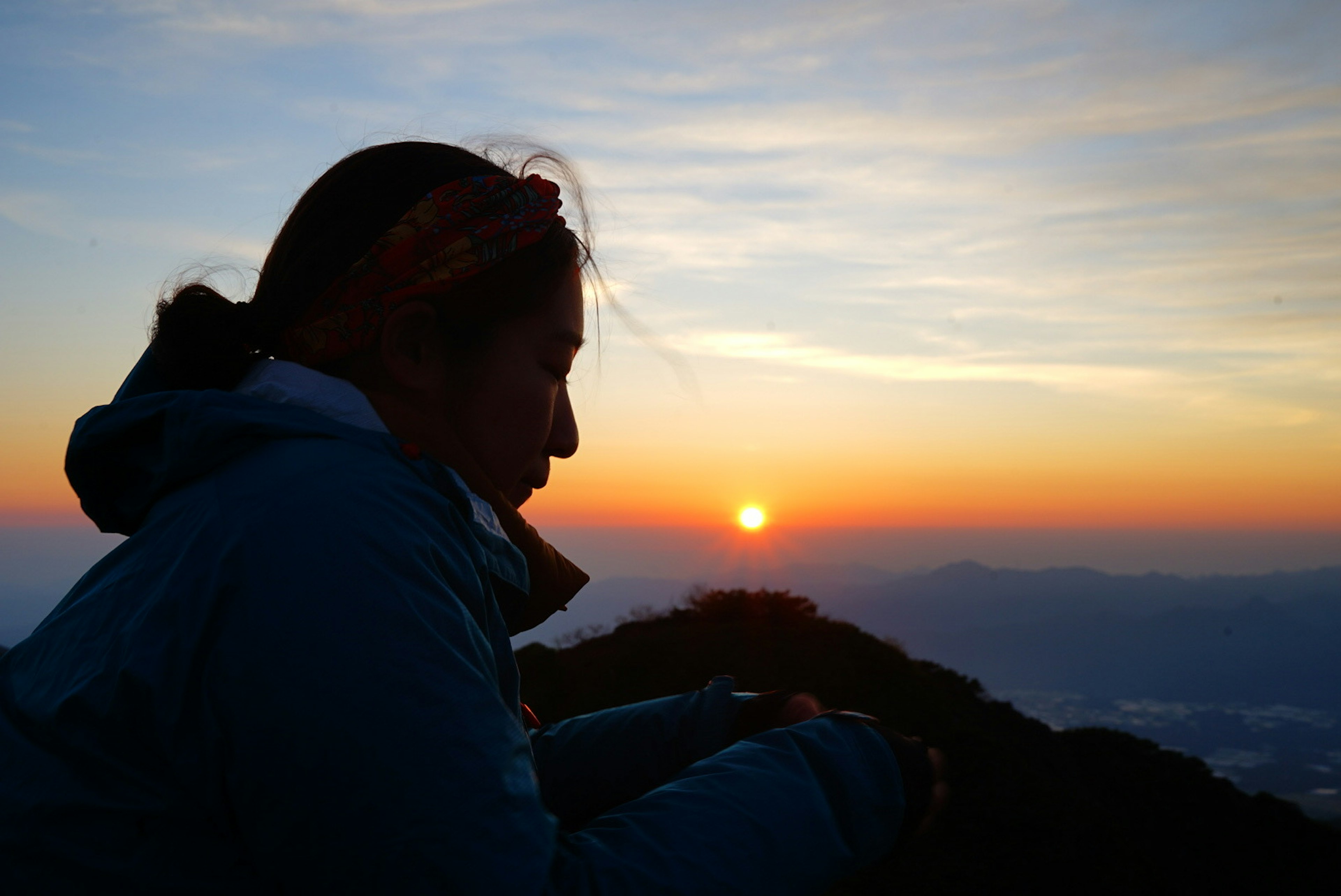 山頂で夕日を眺める女性のシルエット