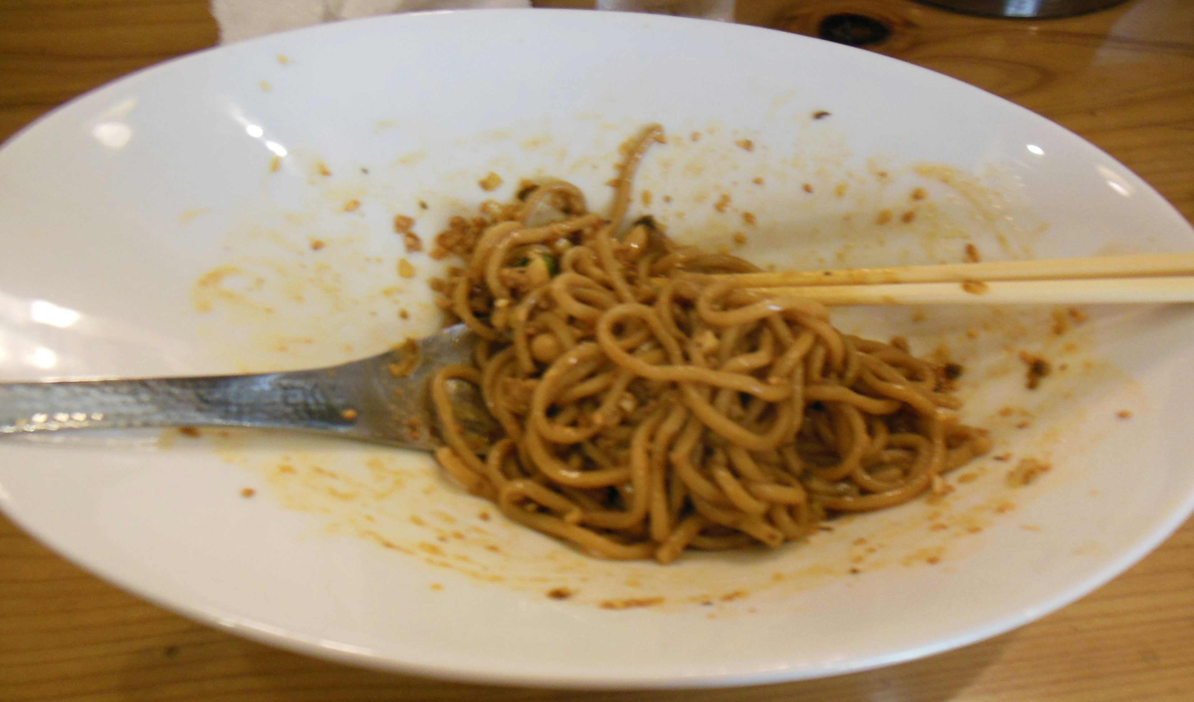 Assiette de yakisoba à moitié mangée avec des baguettes