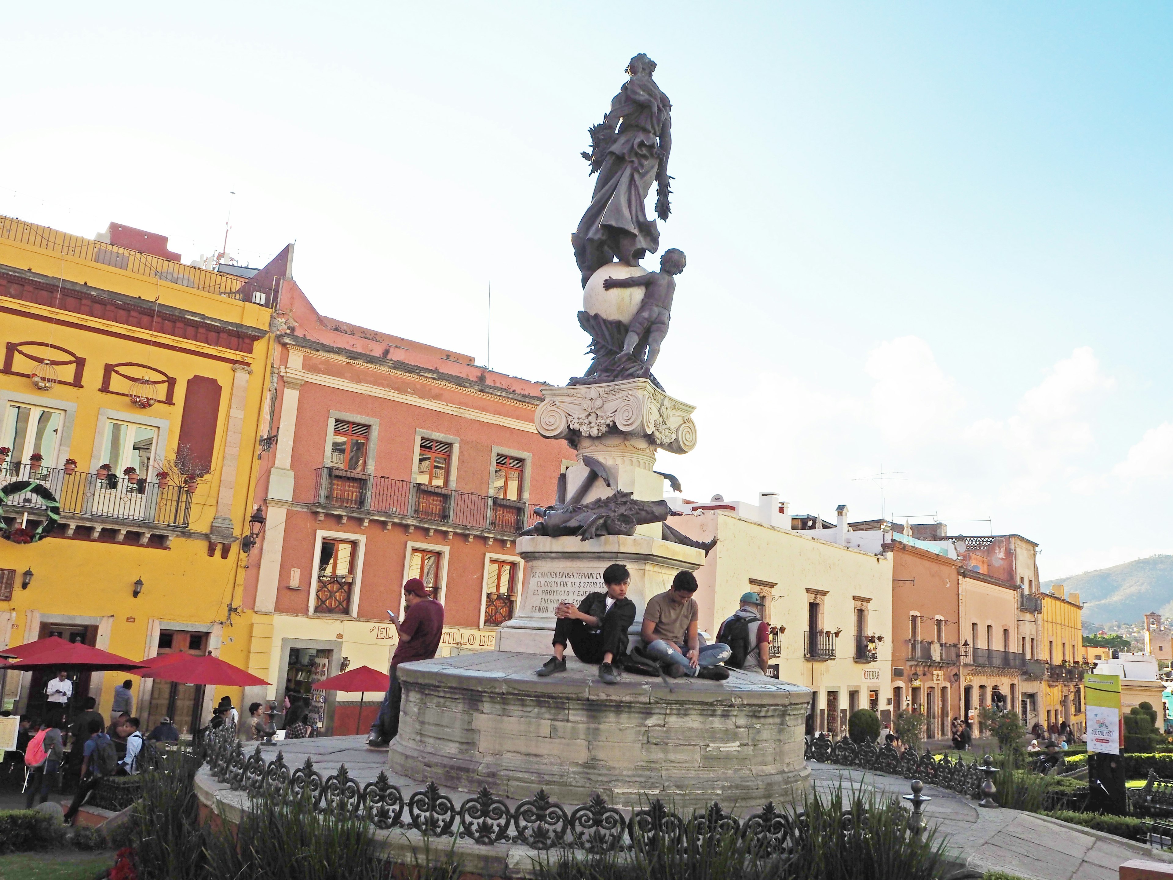 Una piazza vivace con una statua prominente e edifici colorati