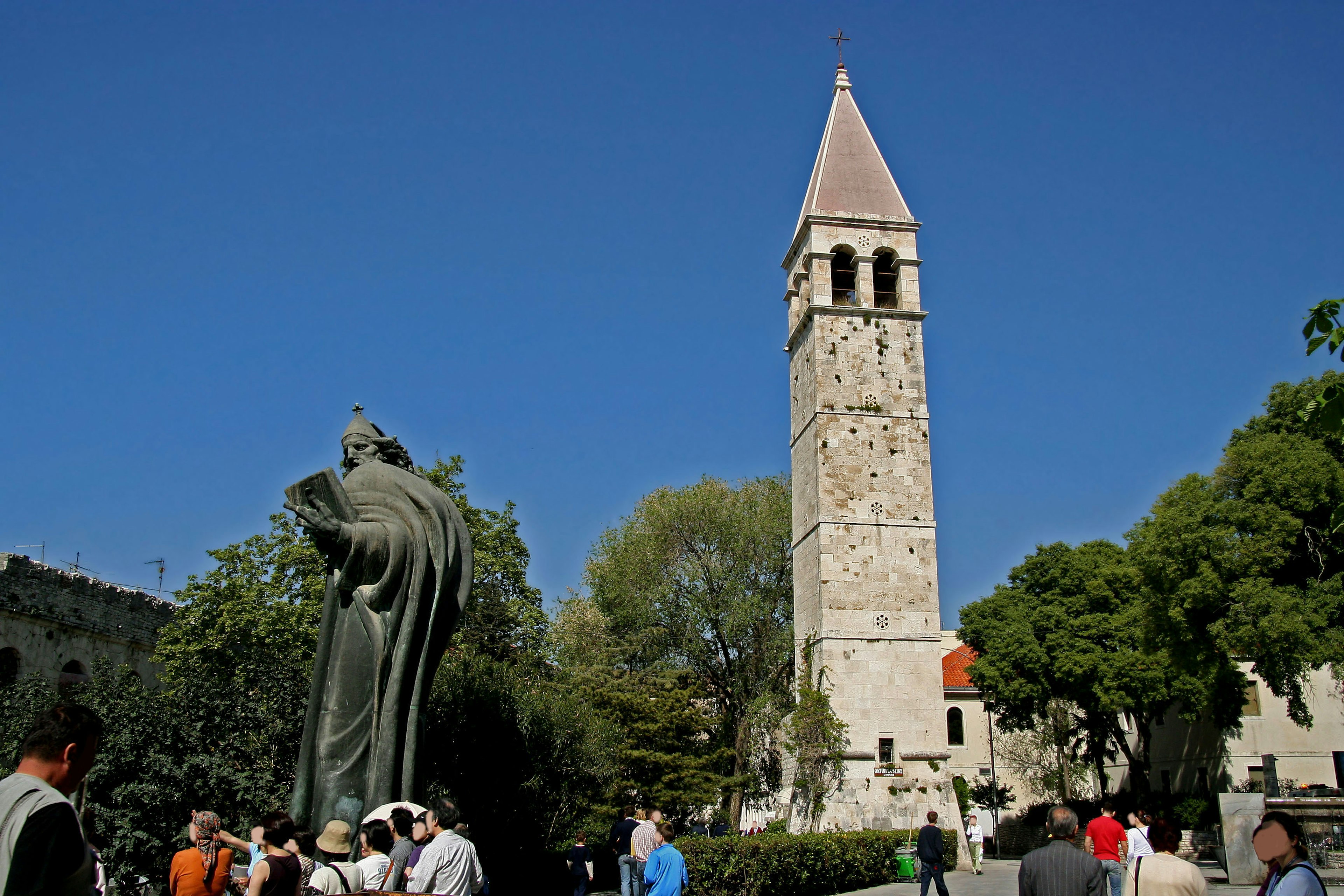 Landschaft mit einem historischen Turm und einer Statue auf einem Platz