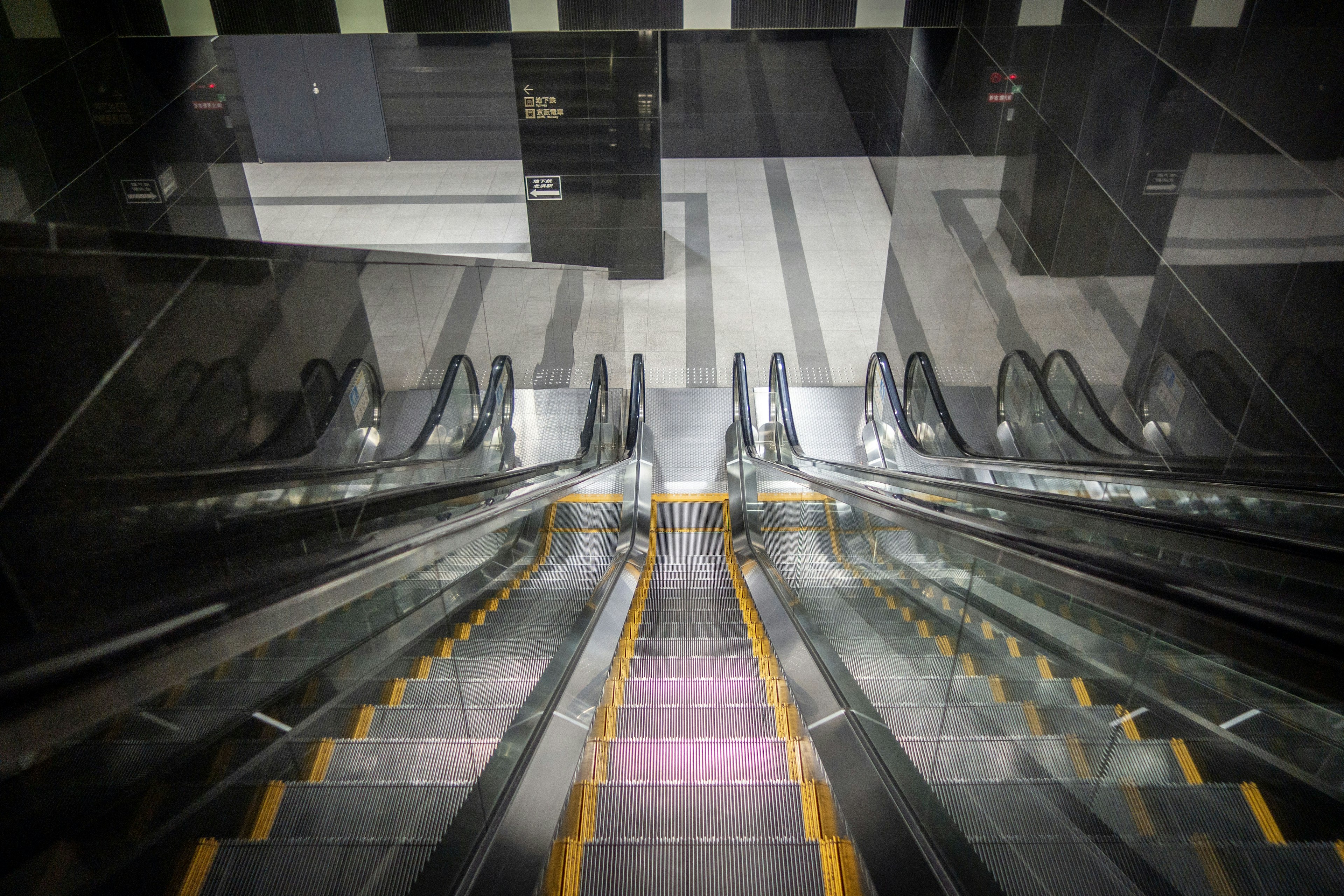 Escalera mecánica descendente con diseño moderno y reflejos en el vidrio