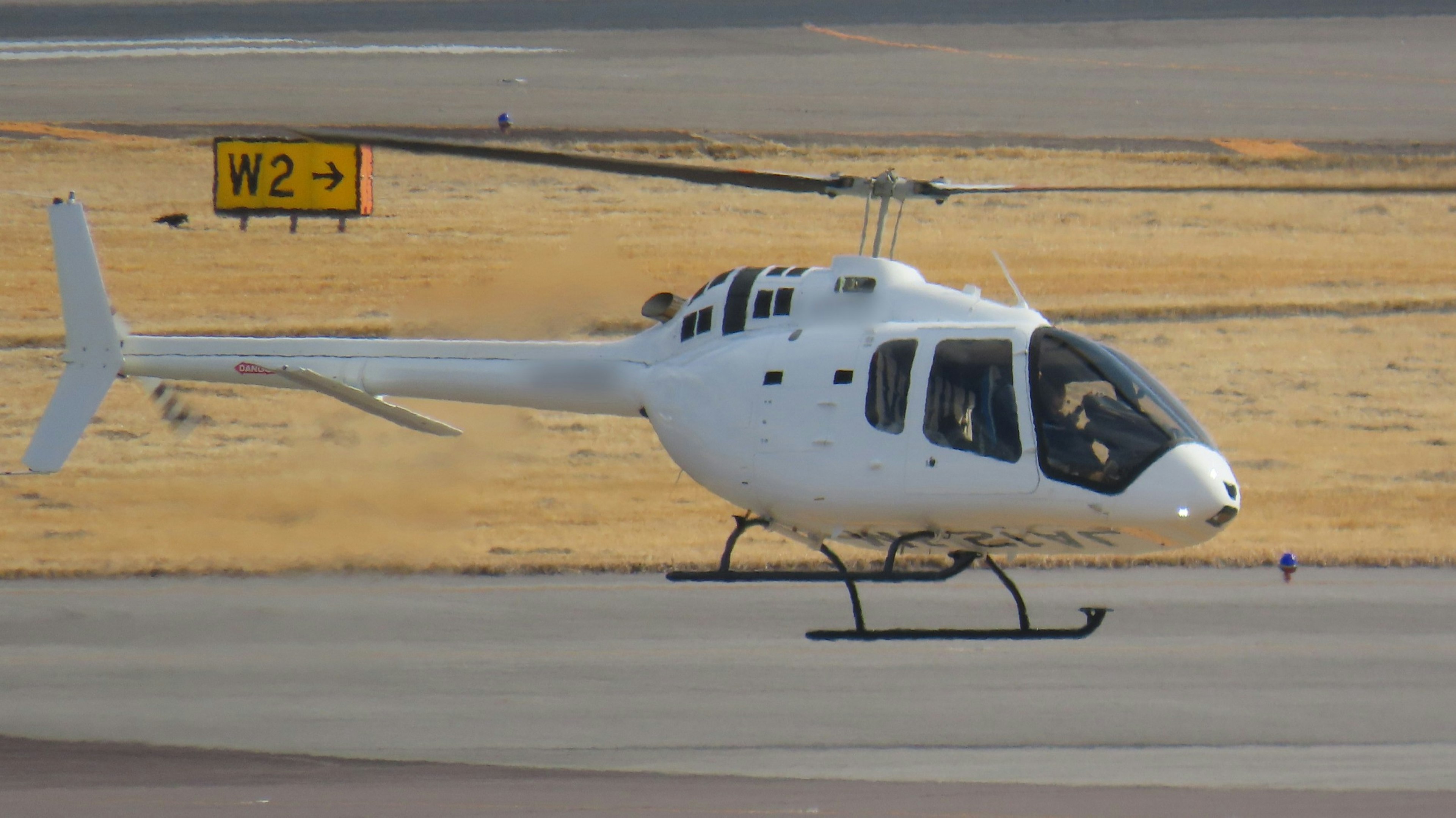 Ein weißer Hubschrauber, der sich auf den Start auf der Piste vorbereitet