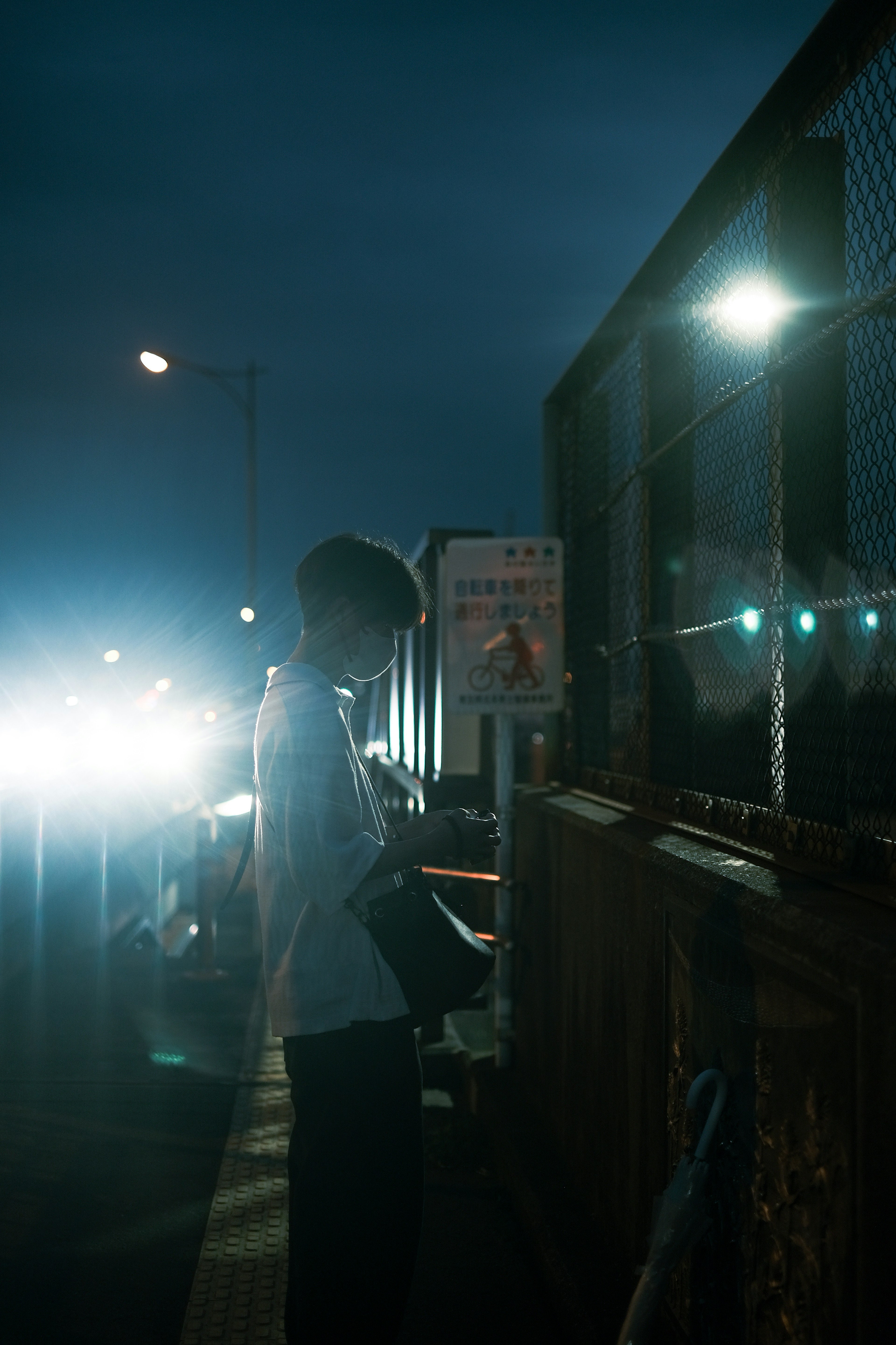 Silhouette of a person holding a smartphone in the night with bright lights