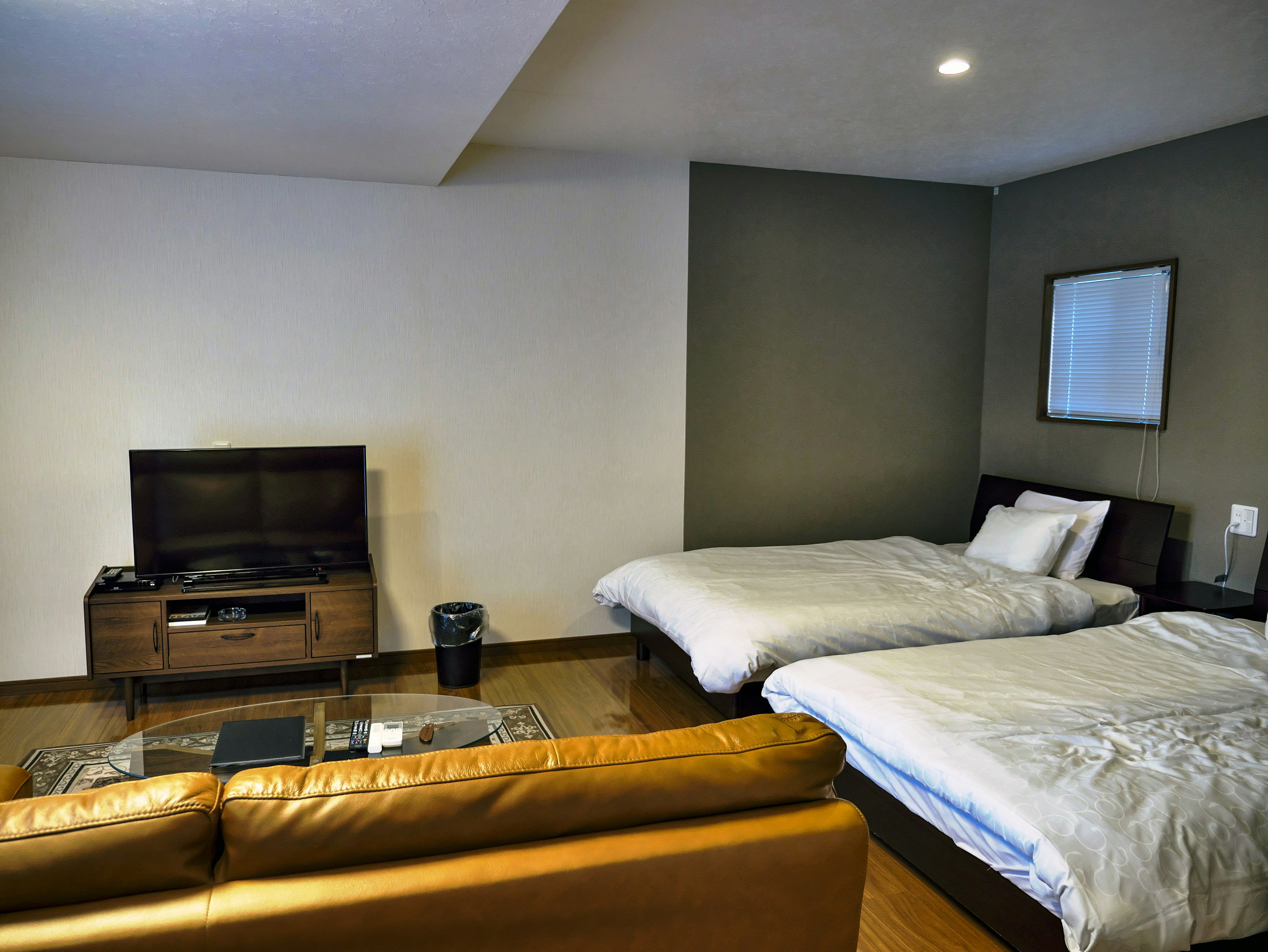 Modern hotel room featuring two beds and a sofa