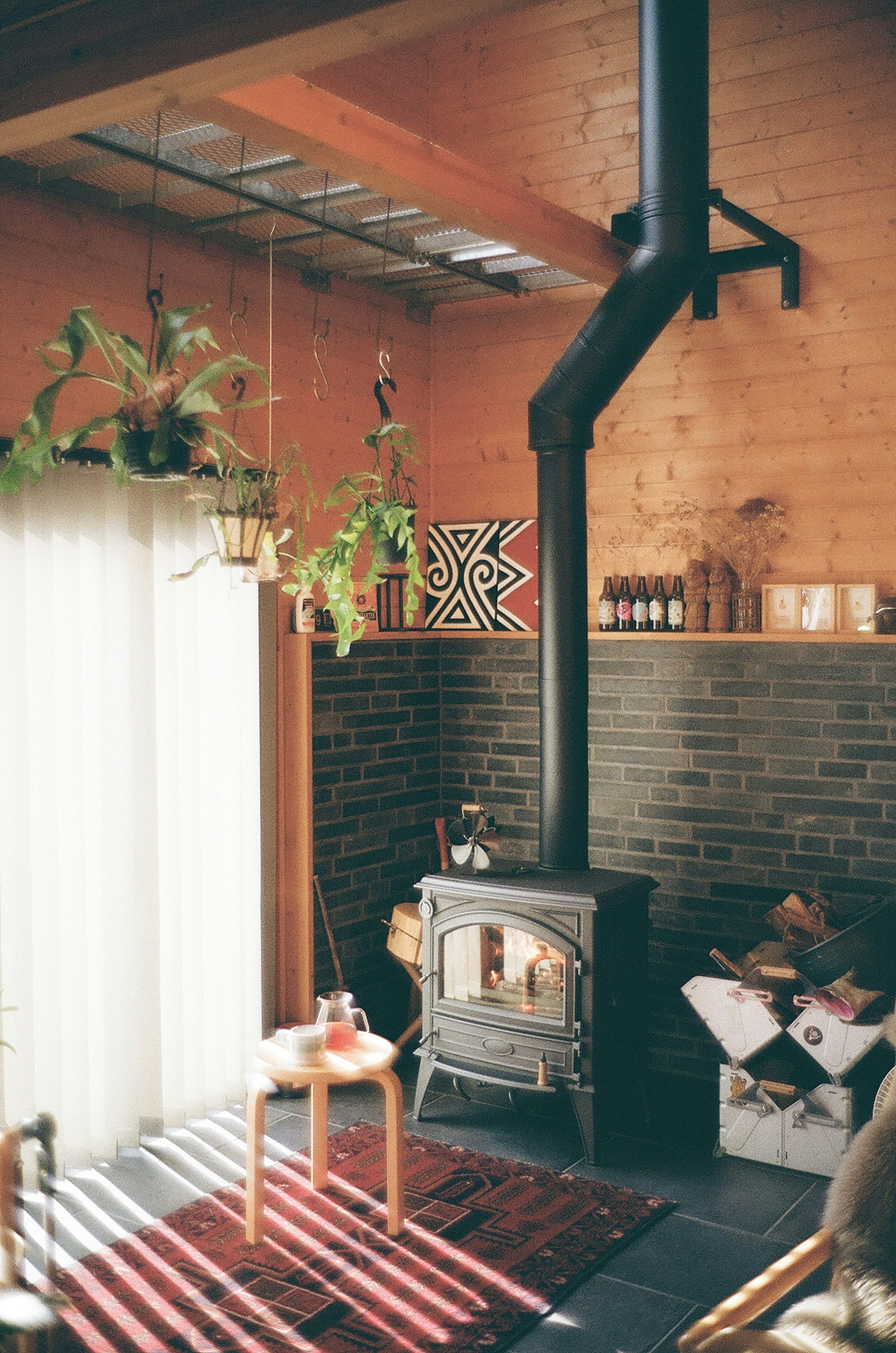 Gemütliches Wohnzimmer mit Holzinterieur und schwarzem Ofen natürliches Licht, das durch das Fenster strömt