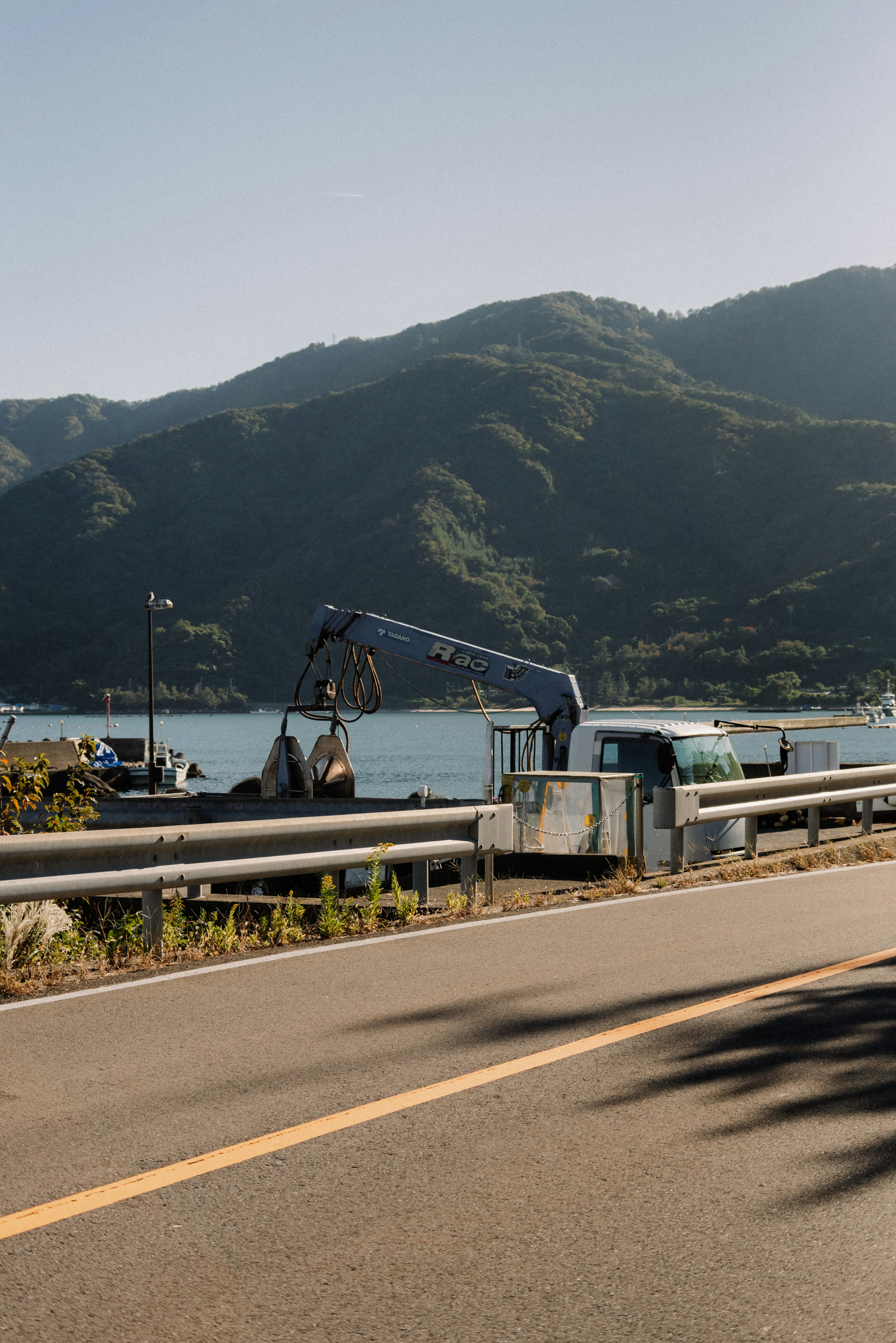 山々に囲まれた湖の近くで作業するクレーンとトラック