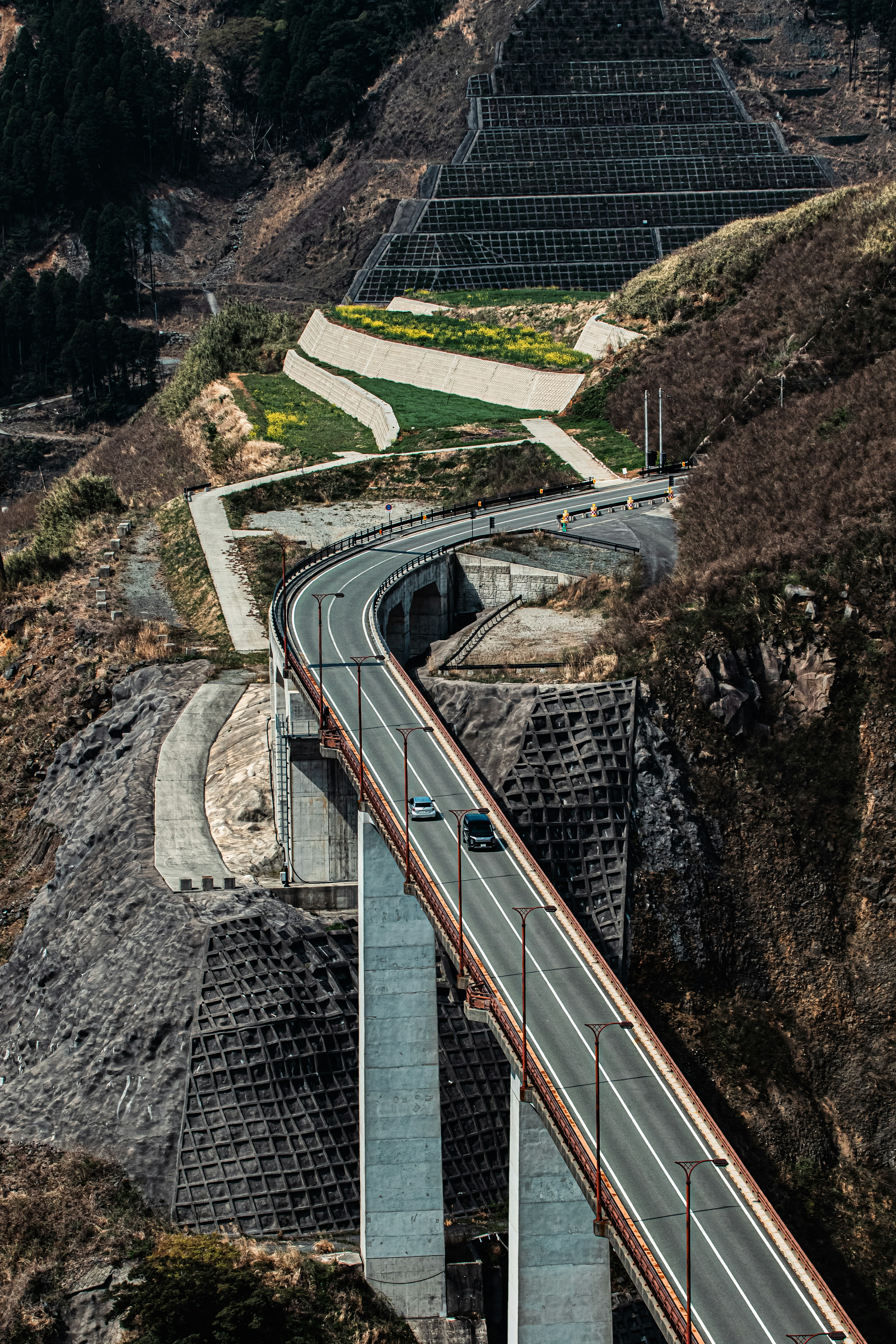 Un pont moderne et une route sinueuse le long d'une pente de montagne