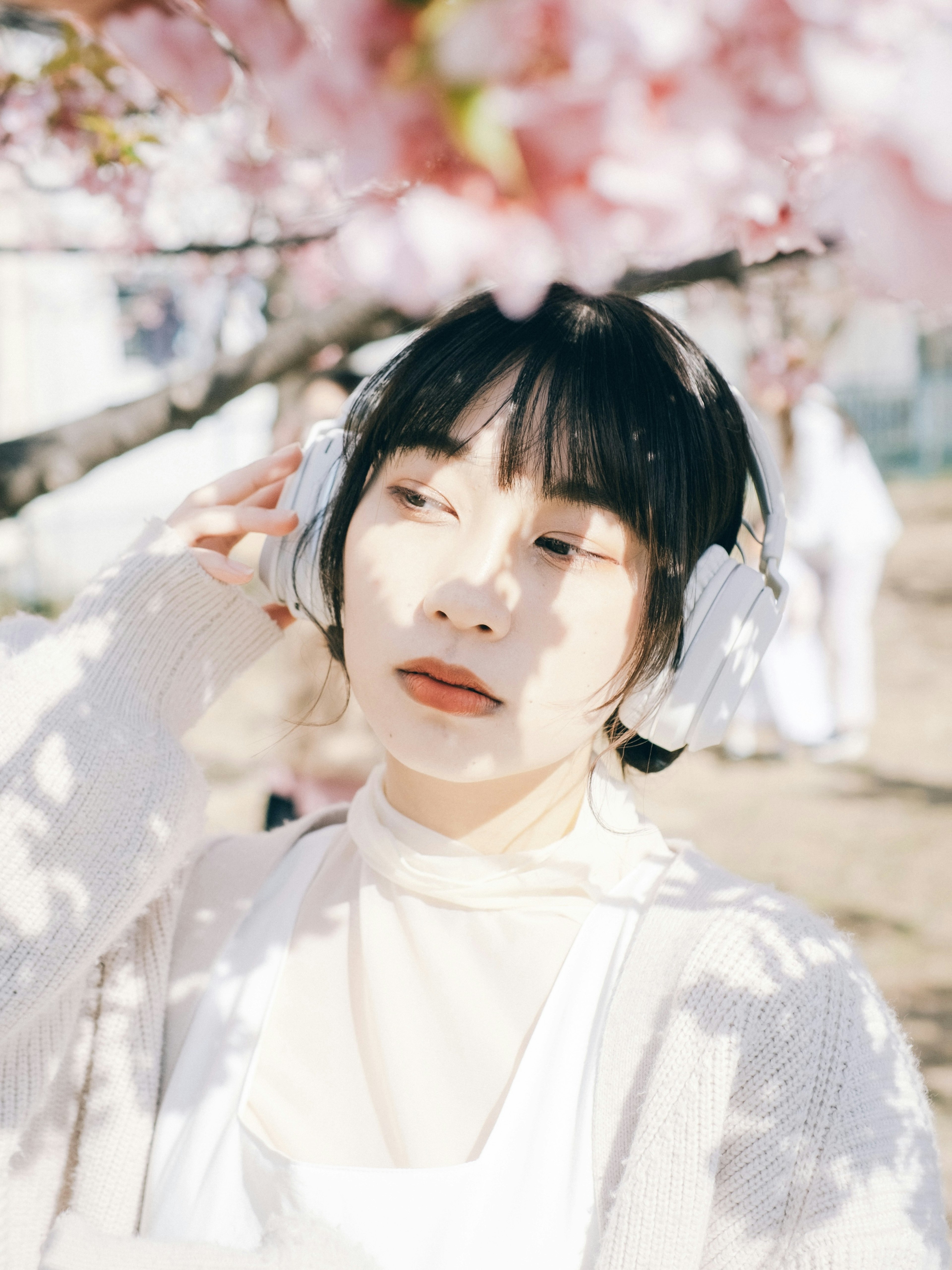 桜の花の下でヘッドフォンをつけた女性のポートレート