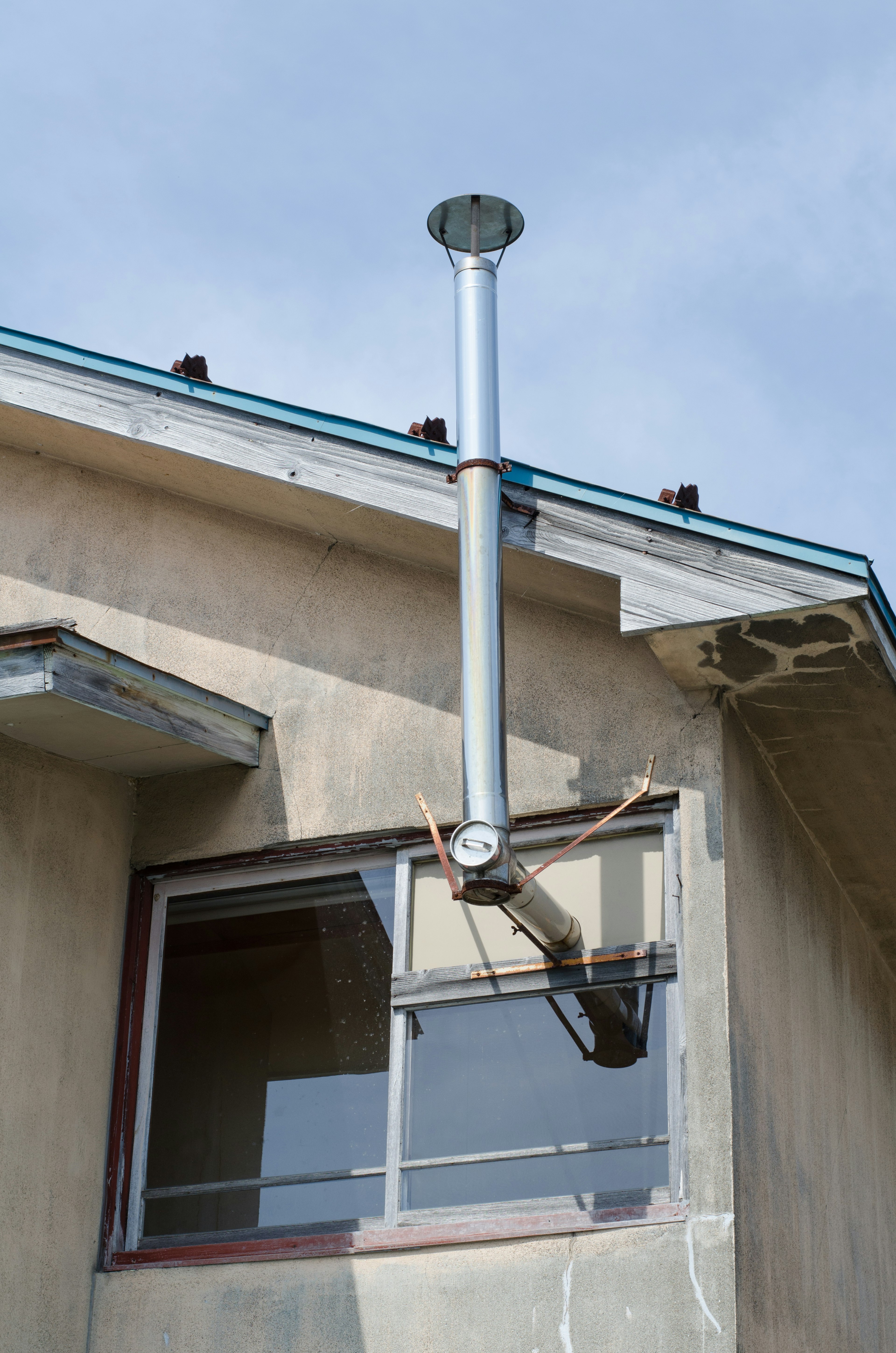 Metal chimney installed outside a window with building exterior