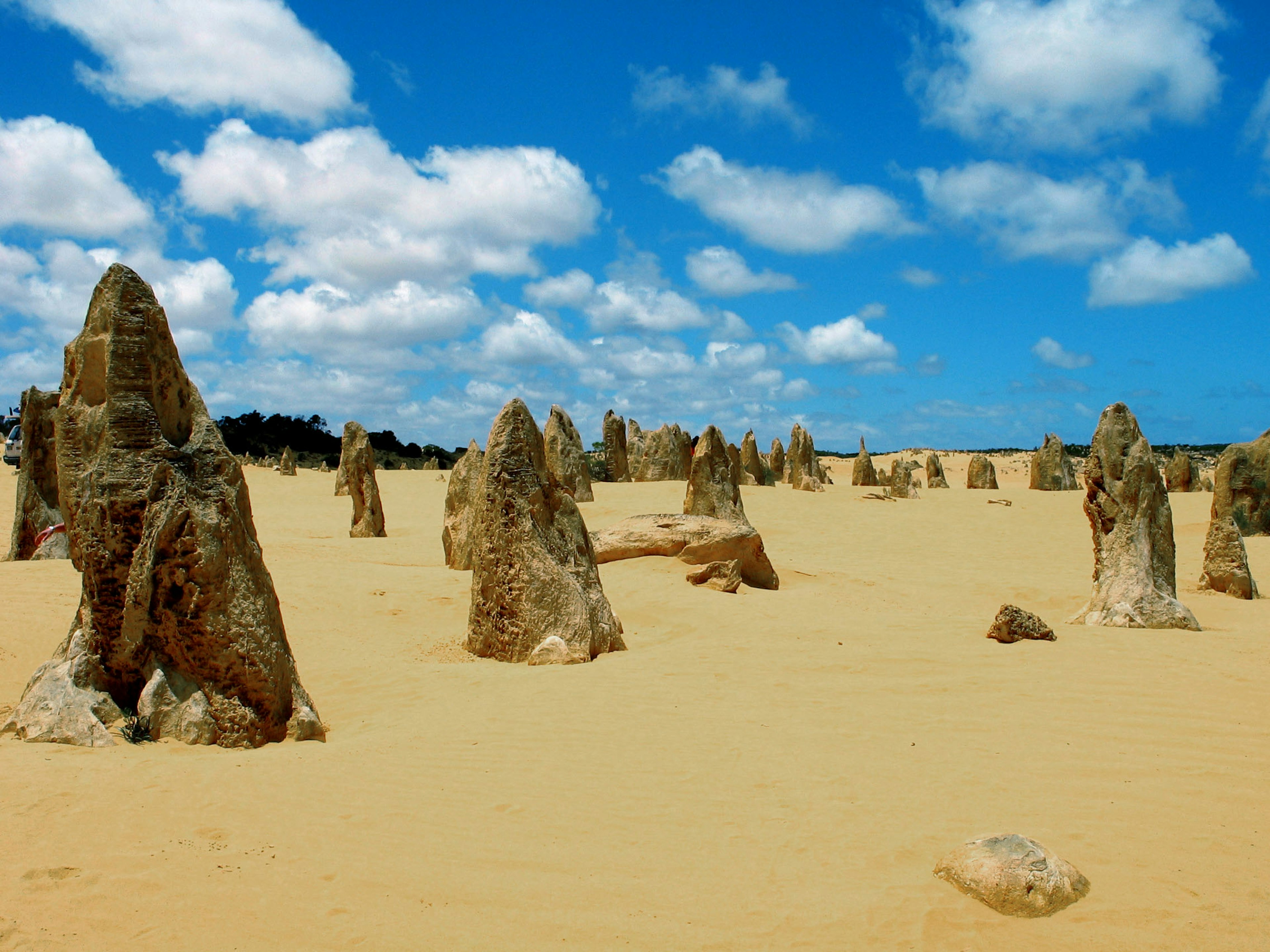 A vast desert landscape featuring unique rock formations and a bright blue sky