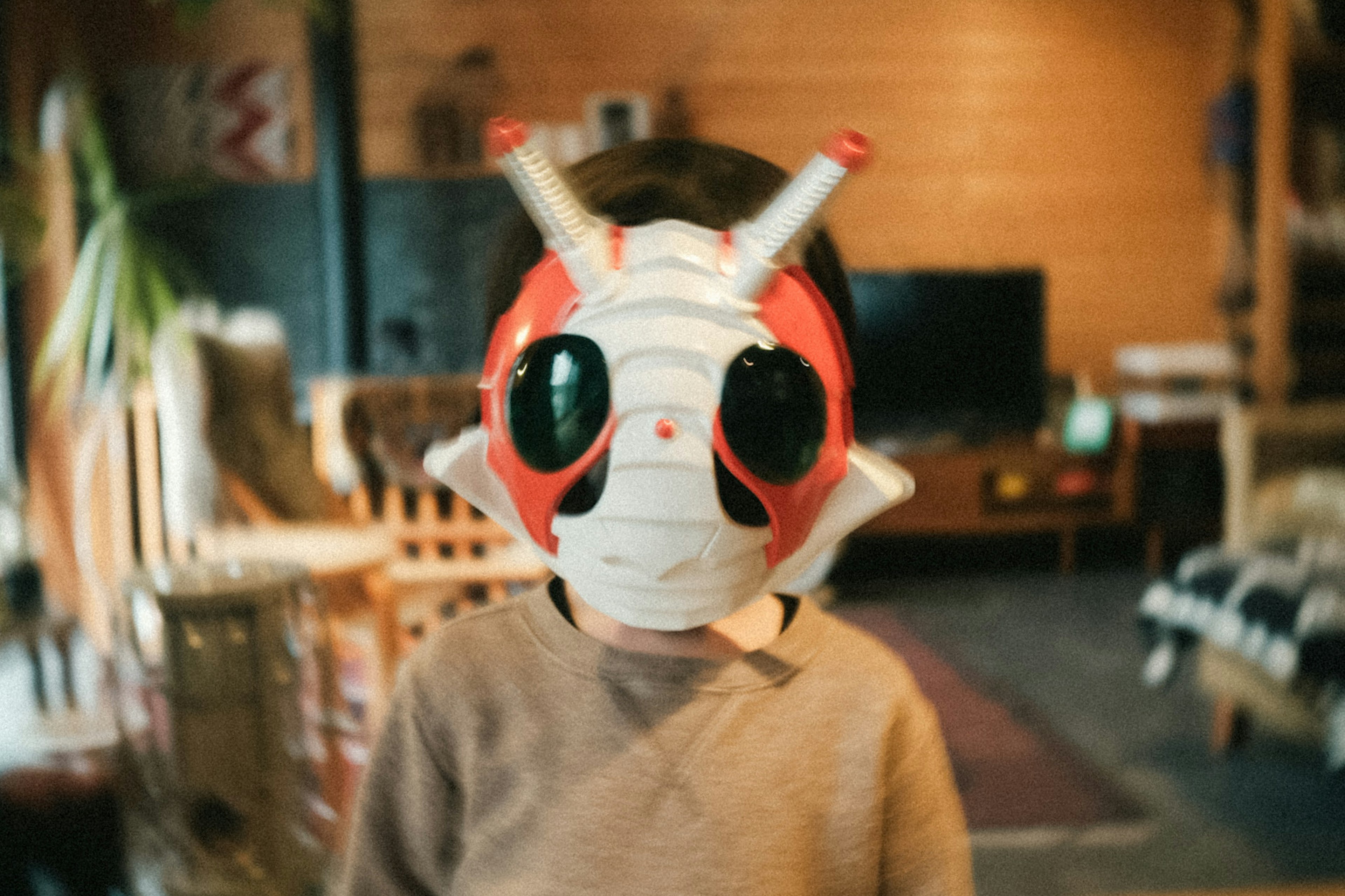 Child wearing a unique insect-themed mask in a cozy indoor setting