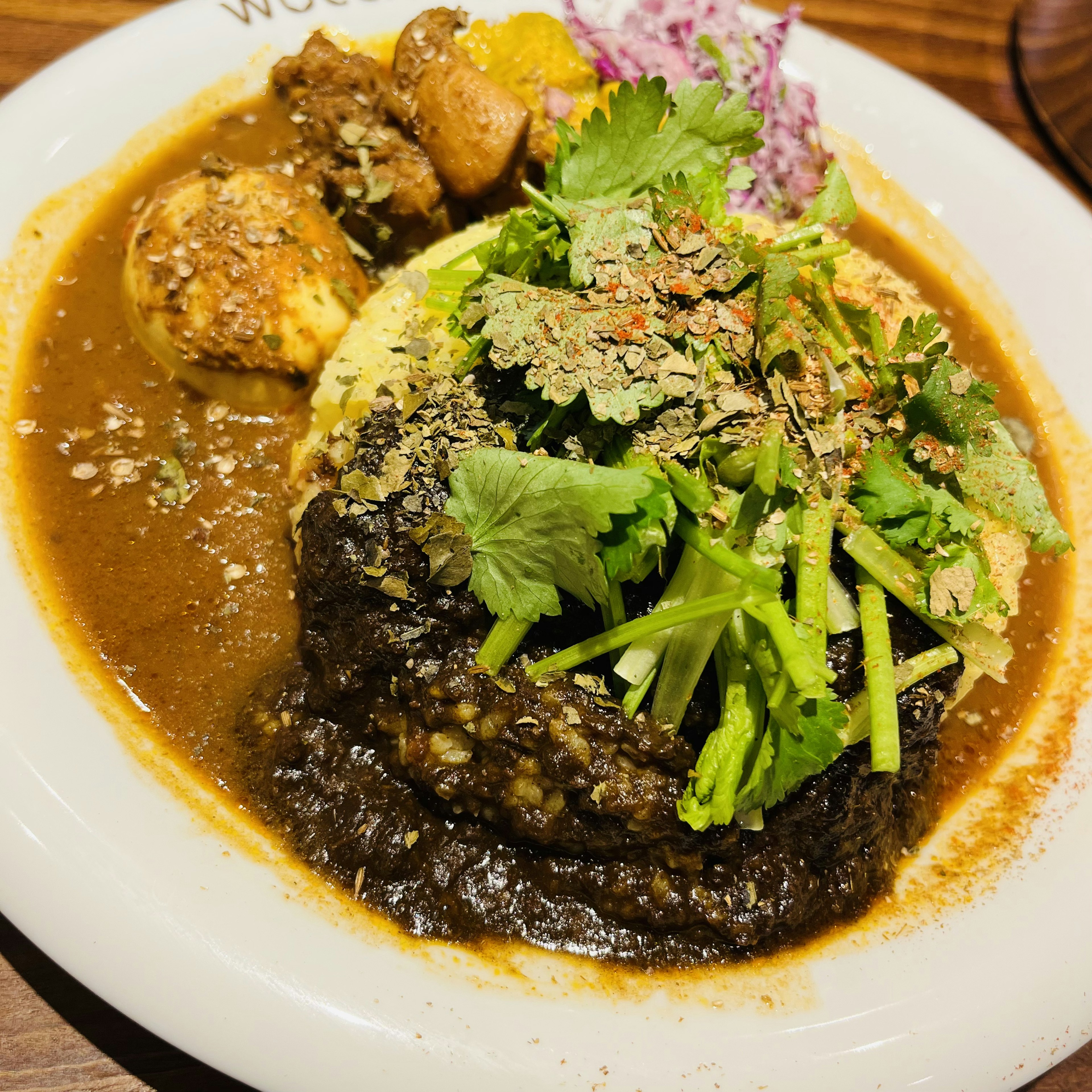 Hidangan nasi yang dihiasi dengan herba segar dan sayuran dalam saus kari pedas