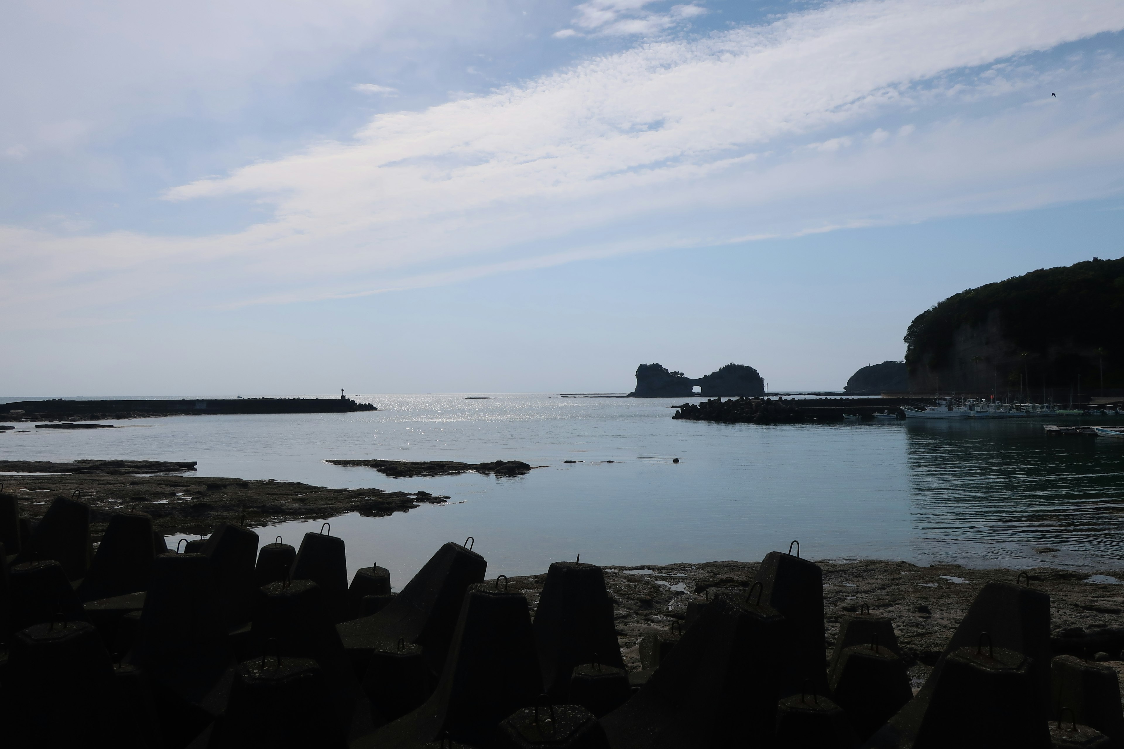 Paysage de mer calme et ciel bleu avec une côte rocheuse visible