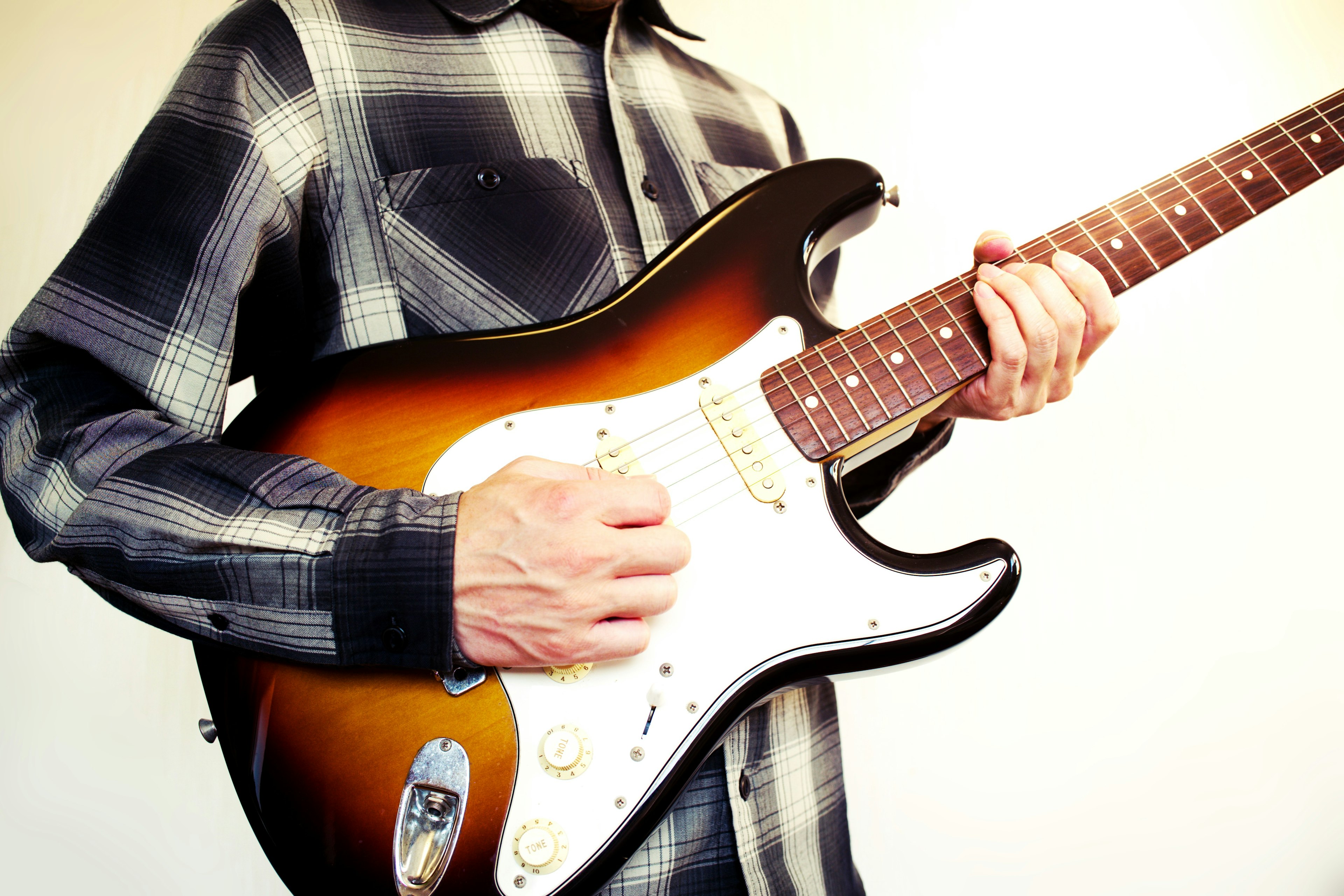 Close-up of a man playing a Stratocaster guitar