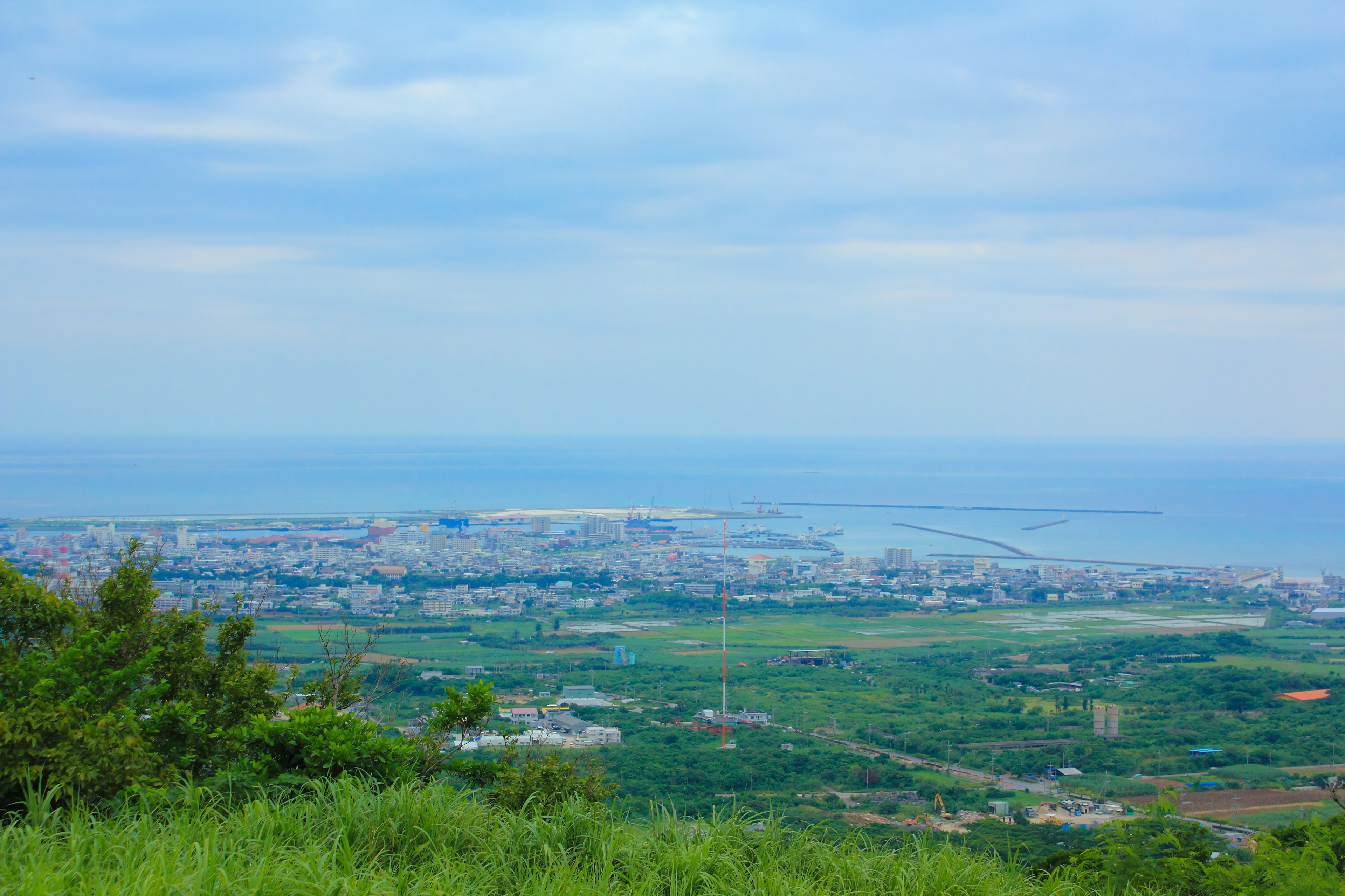 Vue d'une ville côtière sous un ciel bleu collines vertes et large mer visibles