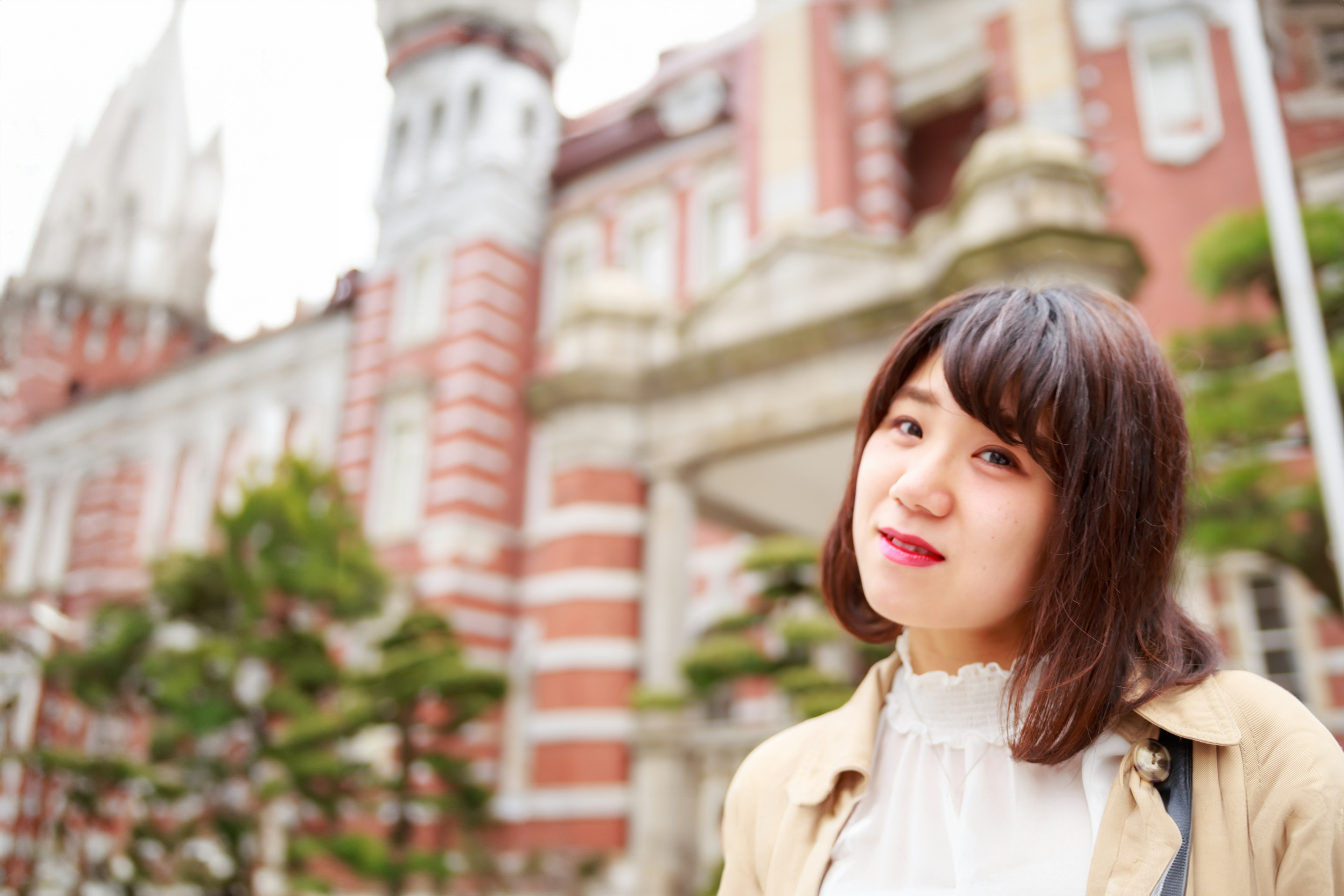 Una mujer sonriendo frente a un edificio de ladrillos rojos con una arquitectura intrincada